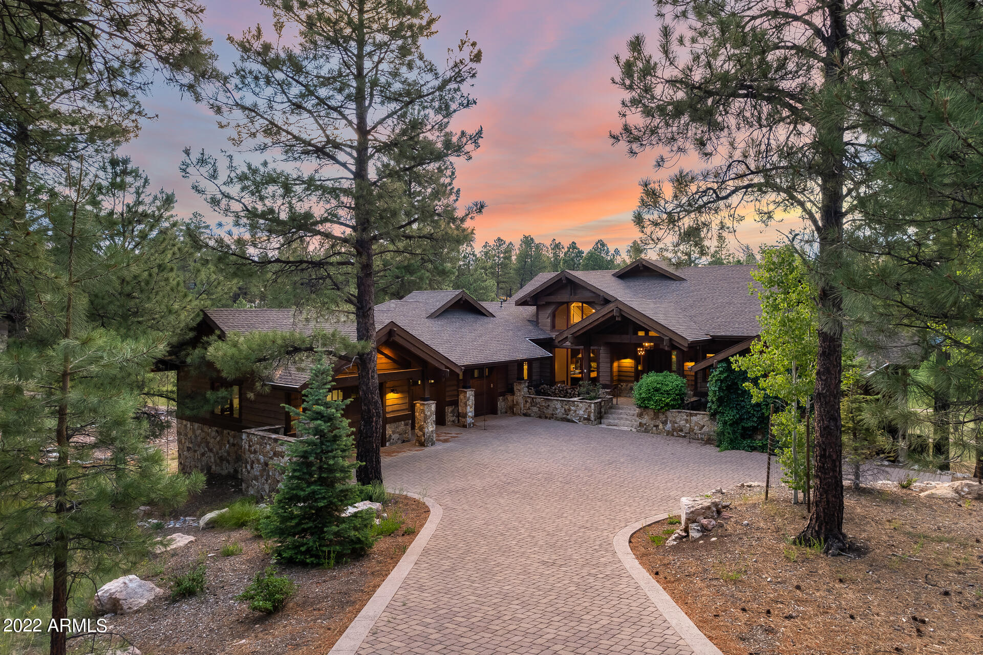 This incredible luxury home in Flagstaff's coveted Pine Canyon community features breathtaking mountain and golf course views! The custom cabin-style home is one of the best lots in all of Pine Canyon and is nestled in a private cul-de-sac, surrounded by beautiful pine trees! The interior features vaulted ceilings, hard wood and stone flooring, as well as 5 spacious bedrooms with private en suite bathrooms. Three of the bedrooms are located on the main floor with one queen bed, a king bed and another king bed in the primary bedroom. The luxury primary bedroom has a gas fireplace, walk-in closet, resort-like en suite and a separate exit to the deck. Your large great room showcases exposed beams and a gorgeous wood-burning fireplace. The gourmet kitchen boasts stone countertops and backsplash, stainless steel appliances, and a huge island with breakfast bar seating. The basement features a bonus room with a cozy gas fireplace, two more bedrooms with a queen and king bed, and an additional room attached to the downstairs master that has 3 twin beds. Outside, your wrap-around deck and outdoor living area features a stone fireplace, built-in BBQ, paver patio and remarkable golf course views. The separate den also showcases golf course views and has a private entrance from the patio - perfect for a home office, game room or gym! Plus, the home is available fully furnished. This luxury home truly is a must-see!