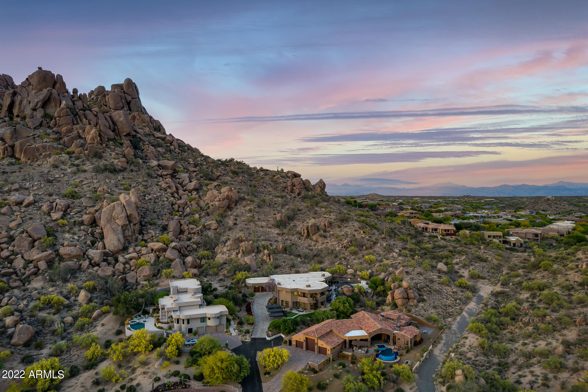 Welcome home to this fully remodeled hillside property with resort style grounds! Some of the most incredible views of Arizona you can find, this home is one of only grandfathered-in non-HOA  luxury homes in Troon, yet still nestled behind the gates for privacy and security. This home boasts 6 en-suite bedrooms plus 2 additional half bathrooms with the master bedroom being tucked away with its own den. The kitchen is equipped with Wolf, Sub-Zero & Gaggenau appliances, a large waterfall island, and large butler's pantry to entertain all of your guests. Hop in your golf cart over to Troon Country Club to get a round in, or just stay home and practice your putting game on your personal putting green. This home is perfect for entertaining with the resort style yard featuring commercial grade misting system, outdoor fireplace, beautiful water feature and outdoor kitchen. The heated pool and spa surrounded by the signature Troon boulders offers a complete tranquil sanctuary when you want to get away from it all.