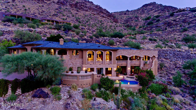Both mountain and city light views abound from this timeless, spectacular estate designed by Lee Hutchinson. From the moment you stroll through the front gates, past the waterfall built into the mountain, you will be intrigued. You will notice quality and detail in every part of the home, right up to the rarely used slate roof! Featuring dramatic European ceiling treatments with 5 custom stone fireplaces. Large dining room opens to an enormous great room, perfect for entertaining and capturing the stunning AZ sunsets. Hand crafted Alder arched French doors span 13ft tall in the great room.  A wood paneled library is located right off of the expansive master suite.  Library and main living areas are all positioned nicely on one level of the home, capturing views from every room. Just a few steps below the main living area boasts a 2,200 bottle wine cellar which includes a tasting room inspired by a restaurant in France. Your guests will enjoy privacy on the lower level of the home with 3 en-suite guest rooms, game room and private living room, all expanding on to the patios and swimming pool. Covered balconies are situated all around the home to capture the true hillside experience.