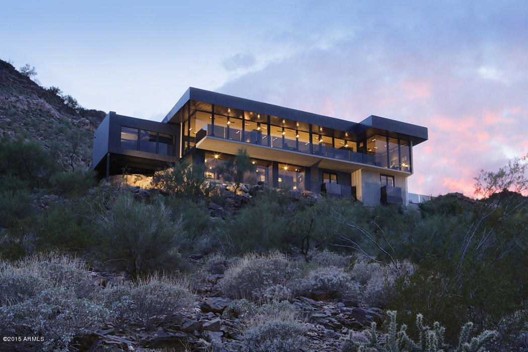 Newly completed ground-up rebuild is all about the views.  Classic, contemporary styling and walls of glass give this home a cosmopolitan feel in the desert.  Living spaces are thoughtfully designed and open yet intimate.  The main level features a gourmet kitchen, flexible entertaining spaces, divided by a fabulous fireplace, a jewel-like hidden bar.  There is also a family room/media room that opens to the  pool and patio.  Master suite takes full advantage of breathtaking views.  Master bath is elegantly appointed and opens to the pool.  On the lower level, guests will feel right at home with two bedrooms/baths and a living room.  Patios span the length of the home;  the perfect place to enjoy the gorgeous Arizona sunset.  Low maintenance landscaping makes  this a perfect lock & leave.