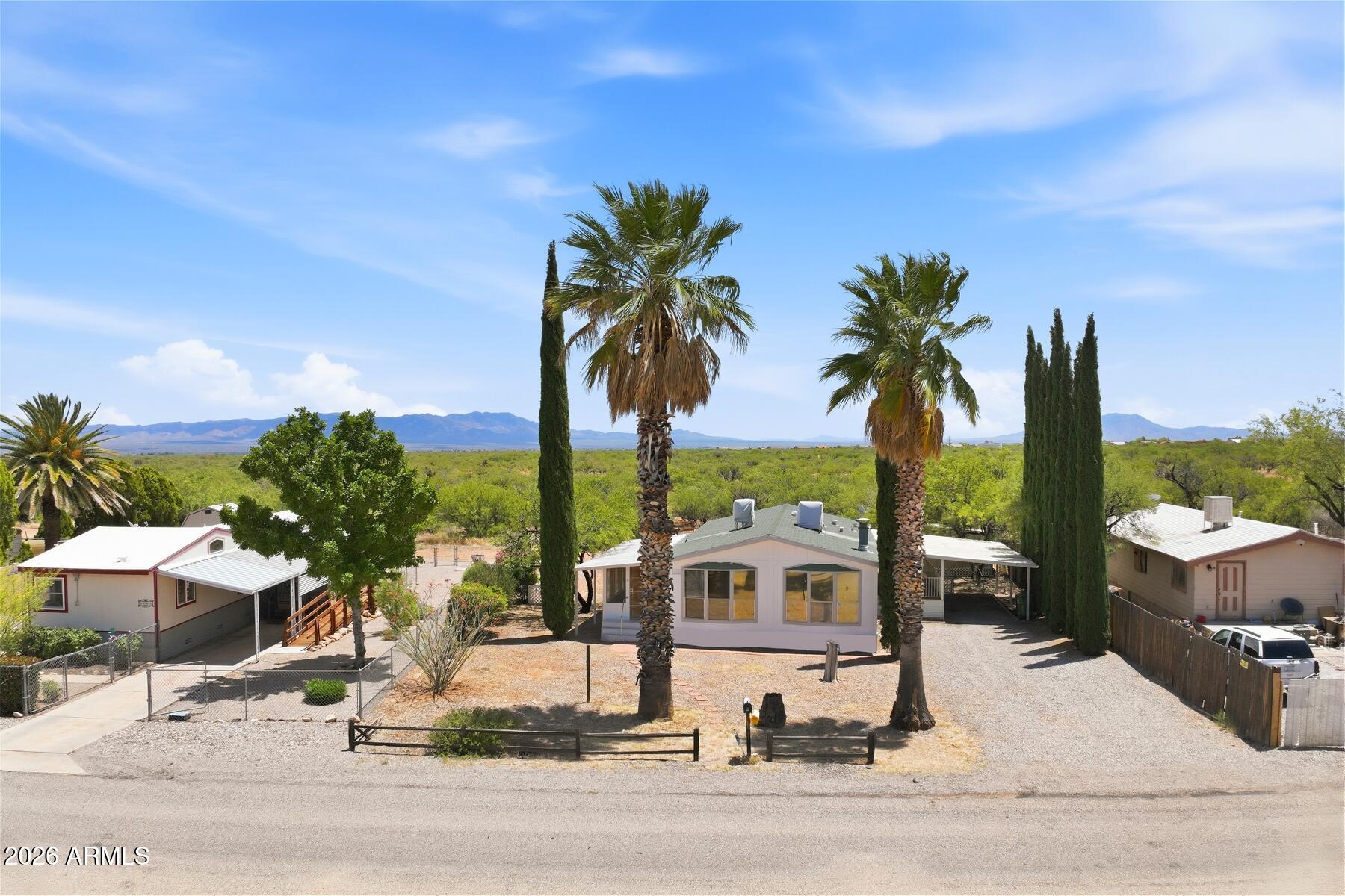 Beautiful 1153 sq ft double wide that feels like a stick built home on one of the neighborhood's largest lots, with an expansive empty field behind. This home offers a covered carport with a sheltered patio deck beneath, an add on room for relaxation, an Arizona Room, and a cozy gas fireplace. The spacious master bedroom features an updated shower in the master bath. Exterior highlights include an expertly manicured yard that boosts curb appeal and easy maintenance. Two storage sheds, very clean inside, provide ample room for a workshop or extra storage. A perfect blend of comfort, outdoor space, and value in a prime spot ready for you to make it Home.