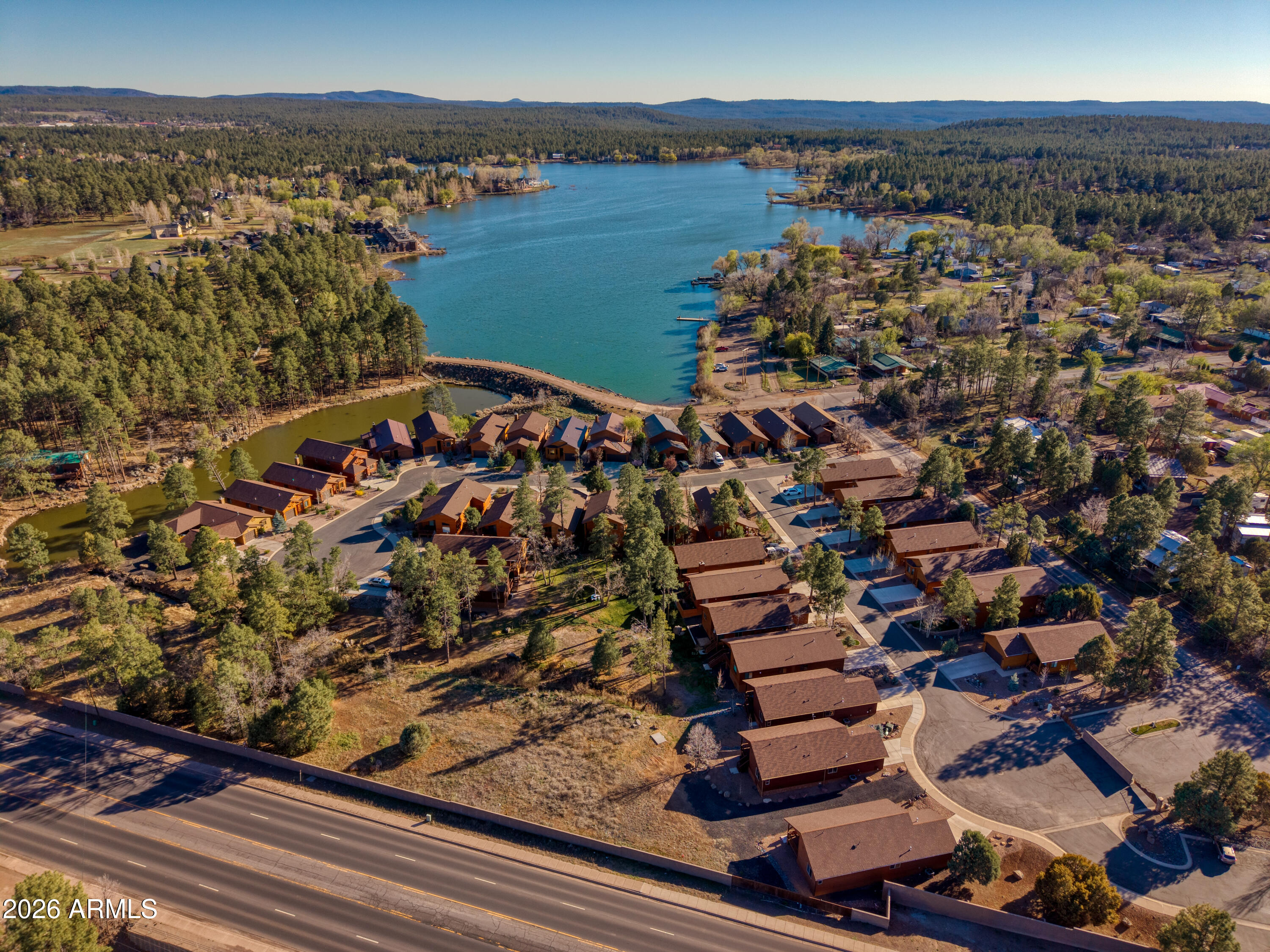 Right next to Rainbow Lake, this gated community of Creekside is the perfect place for water enthusiasts! Take your body board, kayak or raft and enjoy some time on the lake. A former model home, this house has lots of fantastic touches: gas fireplace, under-floor insulation, plantation shutters and zebra shades, stainless steel appliances, RO system, a touch faucet, under-cabinet lighting, new Trex Decking, movable outdoor bench seats, water leak detectors, smart switches and other features that make this home easy to live in full time or lock and leave. The primary bedroom is downstairs, and with the majority of the living space on the main level, it lives very much like a single-story home. Upstairs, you'll find a spacious loft, an additional bedroom, and a full bath--ideal for guests or anyone wanting a little separation and privacy. Outside is a large open green space with trees that make it easy to relax and a large deck made to entertain. Come grab your furnished piece of Pines Paradise