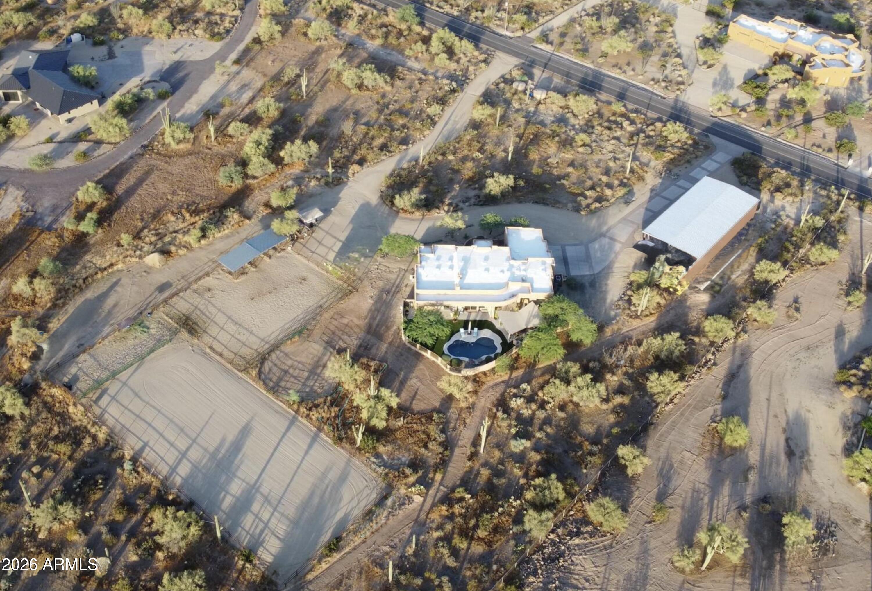 Exquisite custom home in Cave Creek on 3.6 acres with privacy and panoramic mountain views and no HOA. Hacienda style residence with split floor plan and large rooms, beautifully done hardwood floors, beams and corbels, vaulted ceilings, and elegant finishes. The master suite offers scenic views, fireplace, and spacious bathroom. The backyard features a sparkling pool and covered BBQ area with high-grade turf and spectacular mountain scenery. Situated adjacent to Cave Creek Regional Park with extensive trails for horseback riding, hiking, and biking. Features include a horse turnout area with three covered stalls, equipped with water spigot, arena, and a tack shed. There is a 3-car garage and a permitted 3,000 sq. ft. insulated metal building which is expandable.
