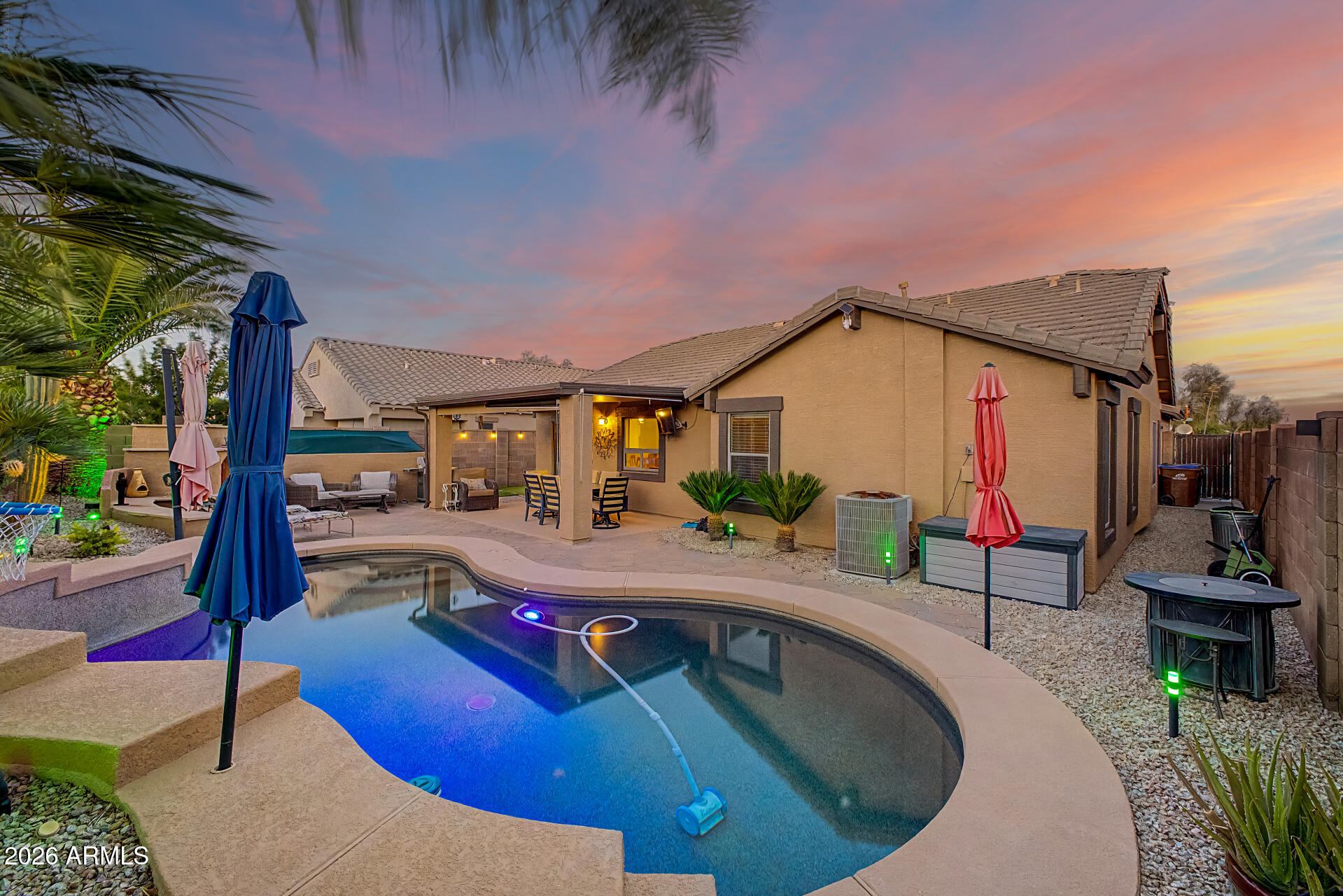 RESORT-STYLE BACKYARD, SPARKLING HEATED POOL, PROFESSIONAL PUTTING GREEN & FIRE PIT. Welcome home to this beautifully maintained 3-bedroom, 2-bathroom home in the highly sought-after Johnson Ranch community. This popular open floor plan features vaulted ceilings, abundant natural light, and a split-bedroom layout for added privacy. The kitchen opens to the main living area and offers granite countertops, a large island, stainless steel appliances, and ample storage. Step outside to your private backyard retreat featuring a sparkling heated pool, professional putting green, covered patio, and a cozy fire pit area, perfect for YEAR- ROUND entertaining, relaxing, and enjoying Arizona living.