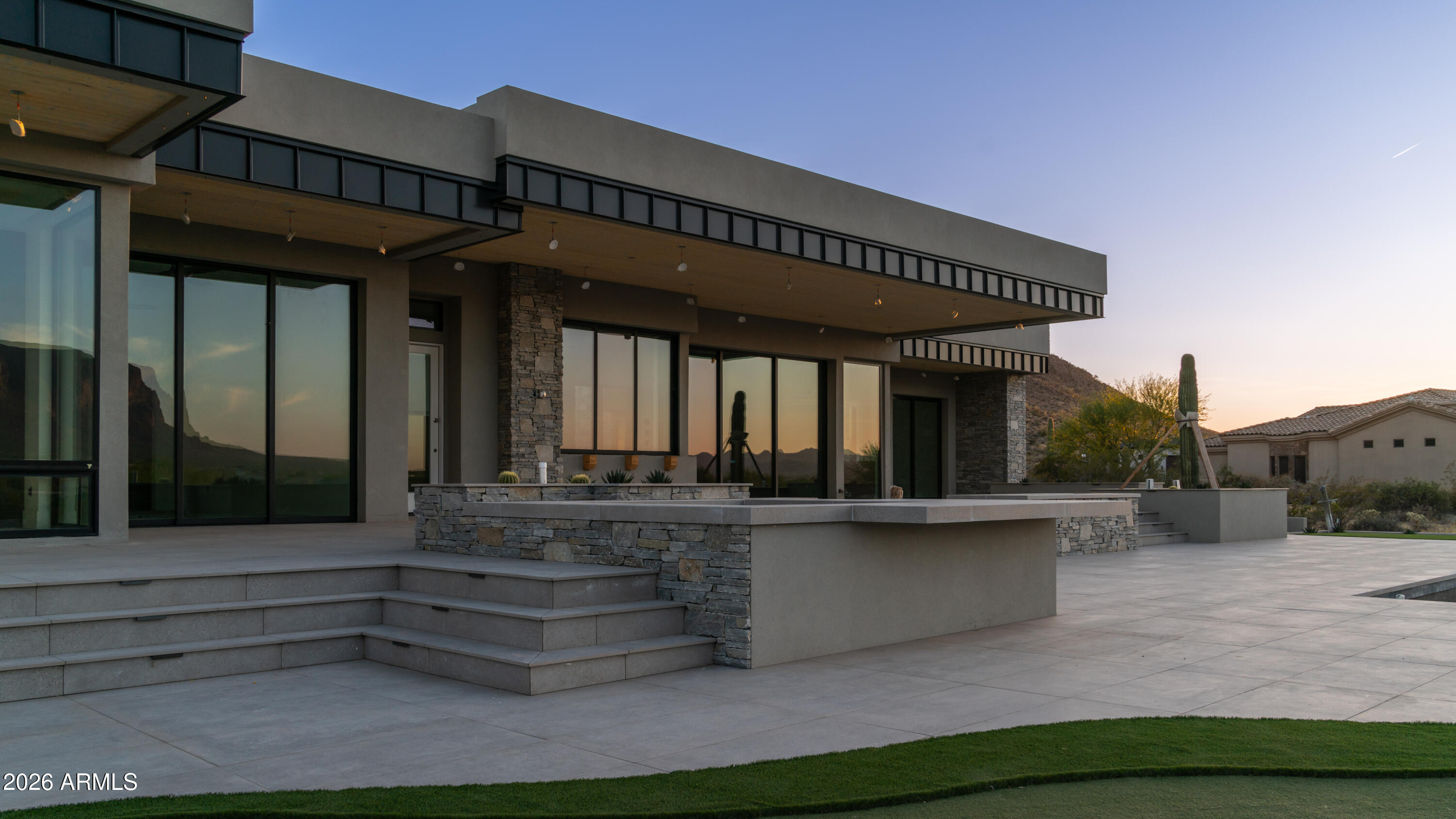 Perched on a nearly ¾ acre elevated lot with stacked retaining walls rising to 14 feet above natural grade, this extraordinary new build captures some of the best Superstition Mountain views available. Floor-to-ceiling glass defines the great room, flooding the space with natural light and seamlessly connecting indoor and outdoor living. The main kitchen is designed for both entertaining and everyday luxury, featuring a bar with a sliding glass pocket door that opens to a 40'' serving counter. A large butler's pantry with a separate food storage pantry provides exceptional functionality. Outfitted with top-tier Wolf appliances, including a split-column fridge and freezer, built-in coffee maker, beverage cooler, ice maker, double ovens, and drawer microwave, no detail was overlooked. A 190-bottle, multi-color LED-lit wine room makes a bold statement, while custom solid panel cabinetry with integrated LED lighting extends throughout the home, including every closet. Tongue and groove ceilings with LED accents flow inside and out, complemented by striking cantilevered entry and patio ceilings. The entire back of the home features covered patios with no columns to obstruct the views.

The resort-style backyard is unmatched, offering a negative edge pool with trough, raised split spa, fire bowl columns, a 10-foot raised firepit, putting and chipping green, and a fully equipped outdoor kitchen with 42" Coyote BBQ, 30" apron sink, and 24" outdoor refrigerator.

Smart and switched controls manage motorized Roll-A-Shade coverings that disappear into the ceilings, patio misting system, and full pool operations. Additional highlights include 2-3cm countertops, an 84" ground-level masonry fireplace, a private Zen garden off the primary bath with outdoor shower and a three-column basalt fountain, Allaire state-of-the-art HVAC system, and a spacious 4-car garage.

This is elevated desert luxury at its finest, thoughtfully designed, masterfully built, and perfectly positioned to capture iconic Arizona views. Estimated completion date June 2026.