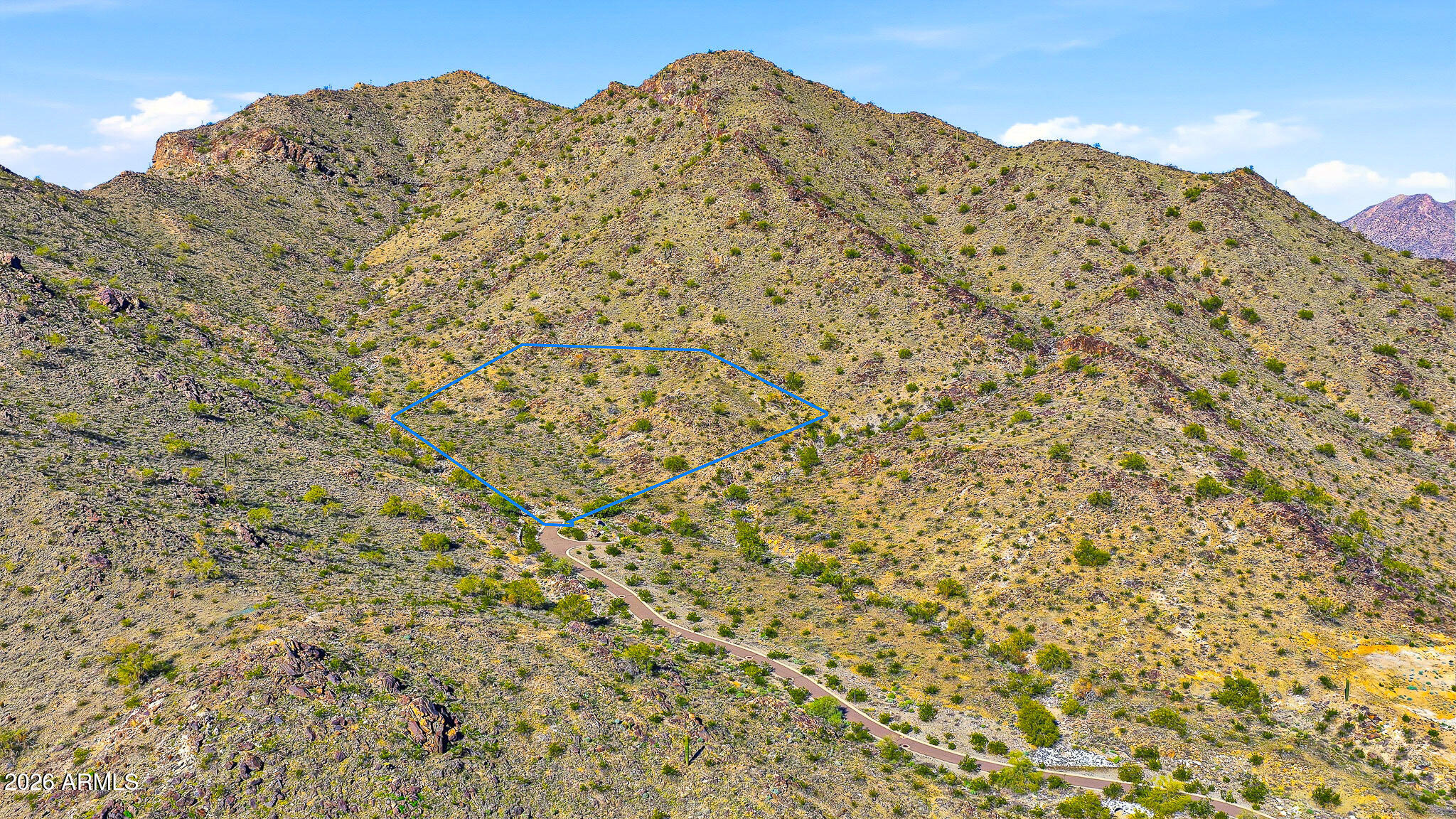 Some seek the convenience of being close to town—shopping, schools, dining, and entertainment just moments away. Others are drawn to wide-open spaces, where nature provides peace, privacy, and inspiration. At the custom enclaves of Verrado, you no longer have to choose. Homesite #1 is nestled within the exclusive Mountain Coves Enclave of Verrado, located at the base of the White Tank Mountains and accessed by a secluded private driveway, offering exceptional privacy and serenity. Ever dreamed of owning your own personal mountain? Spanning an impressive 5.09 acres, this expansive mountainside homesite delivers a rare opportunity to do just that. Surrounded by the breathtaking beauty of the Sonoran Desert, the property perfectly complements Verrado's charming, tree-lined streets and small -town ambiance. The community features over 80 parks and greenbelts, ensuring every home is within two blocks of open space. This premier homesite showcases sweeping panoramic mountain views, sparkling city lights, and unforgettable Arizona sunsets. Verrado is further distinguished by two Tom Lehman-designed championship golf courses, a vibrant City Center with shopping, dining, fitness facilities, and pools, as well as highly rated A-schools. With an active calendar of clubs, events, and amenities, Verrado offers something for every lifestyle. This extraordinary homesite is an ideal canvas for a custom dream home and is sure to impress even the most discerning buyer. Experience the Verrado lifestyle.