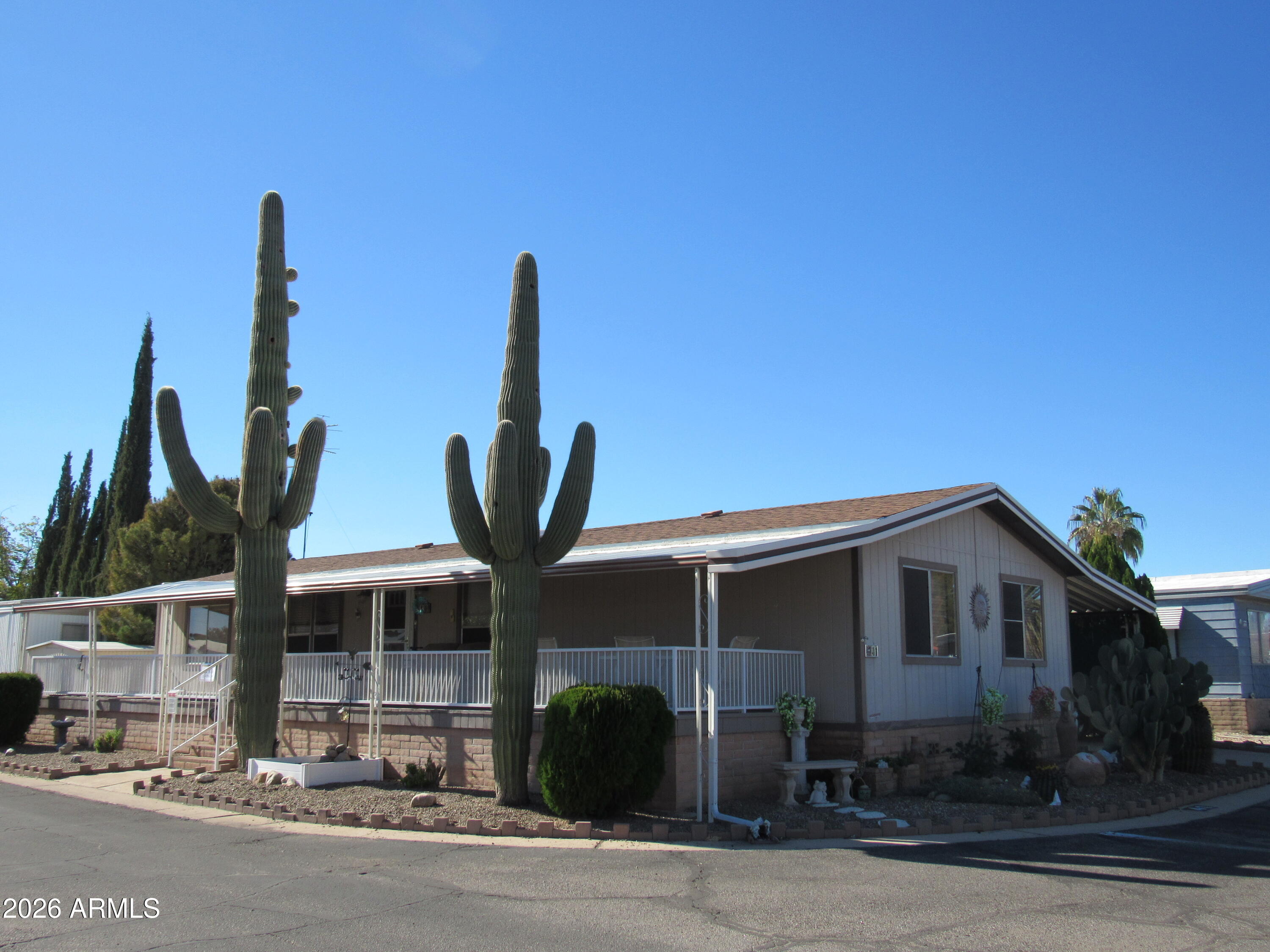 We offer the benefit a walled community, security cameras along with guards. Our pet friendly community features 2 refreshing swimming pools, an arts and crafts center, basketball court, billiards, club house that includes a gourmet kitchen, dry sauna, fitness center, hot tub, library, pickle ball to bocce ball, shuffle board along with professional on-site management. 
Residents may also enjoy community gardening, a patio area along with an array of resident activities. 
We also include a wide range of health, fitness and social programs including water aerobics, bingo, cook outs, dancing, golf cart parades, water volleyball, yoga and much more.   We look out for one another and genuinely care about the community in which we live. Watch the sun rise from the beautiful full length porch on front of house. 
Elegant mirrored walls in living room and dining room. Informal dining just off the kitchen with a China cabinet for even more storage. 
Large refrigerator with extra free-standing upright freezer included. Large laundry room with matching washer and dryer and lots of cabinet space just off back porch of home.
Tiled kitchen and dining room, 3 carpeted bedrooms.  Beautiful cathedral ceilings with 5 ceiling fans throughout.  
AC recently serviced.  2024 new pipes throughout home.  New jetted bath/walk-in jacuzzi tub in primary bathroom. Grab bars throughout.
2 sheds with electricity for ample outdoor storage.  Sheltered, fenced in patio area at end of carport for leisurely activities.