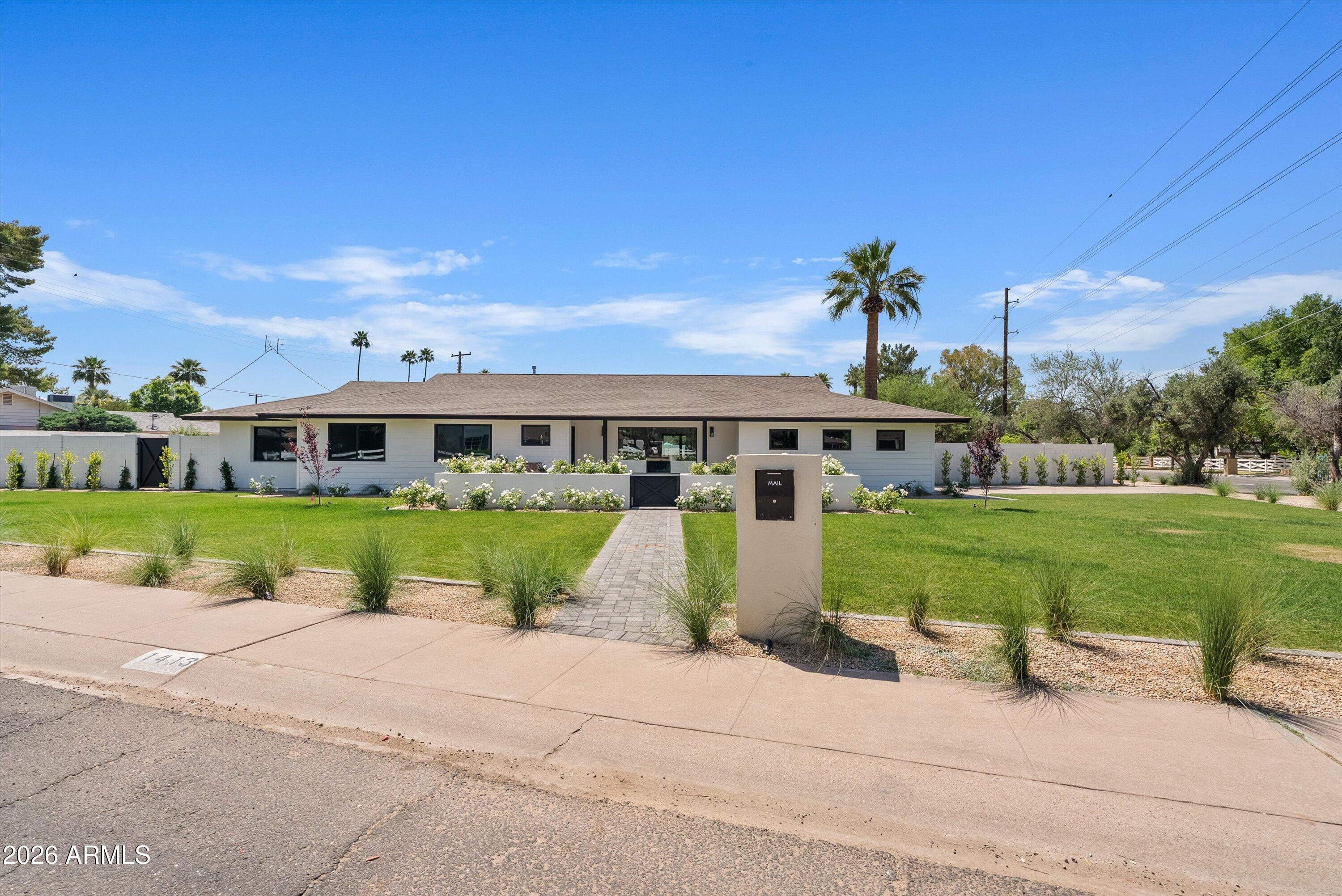 Welcome to 1413 W. Frier Drive in Westwind Estates--an exceptional, fully remodeled ranch-style home nestled in the heart of North Central Phoenix. Set on a spacious 16k, lushly landscaped lot, this 4-bedroom, 2.5-bath residence blends timeless design with modern functionality, delivering a turnkey living experience inside and out. From the moment you arrive, the curb appeal is undeniable. A wide paver walkway leads through an expansive green lawn to a charming gated front courtyard framed by blooming white roses--creating a private, welcoming entrance. The clean-lined exterior, black accents, and manicured grounds set the tone for the thoughtful renovation carried throughout the home. Inside, you're greeted by a bright, open-concept floor plan with wide-plank wood flooring, smooth white- -walls, and an abundance of natural light. The living spaces feel airy and connected, anchored by a sleek modern fireplace with vertical shiplap detail and a mounted TV--perfect for both relaxing and entertaining. The kitchen is a true showpiece, featuring custom natural wood cabinetry, dramatic countertops and backsplash, high-end stainless steel appliances, and an oversized island with seating. A wall of windows and glass doors seamlessly connects the indoor space to the backyard, enhancing the home's indoor-outdoor lifestyle. Adjacent to the kitchen, the dining area is highlighted by designer lighting and views of the pool and yard. The floor plan offers privacy and comfort, with spacious bedrooms and beautifully updated bathrooms showcasing high-end finishes, custom vanities, and clean, modern tile work. Every detail has been carefully curated, from fixtures to flooring. Step outside to your own private retreat. The massive backyard features a sparkling pool, lush synthetic lawn, and ample patio space for lounging or entertaining. The landscaping is fresh and thoughtfully designed, creating a serene and functional outdoor environment. Additional highlights include a large laundry room with custom tile flooring, ample storage throughout, and a 2-car garage. Situated in a highly sought-after neighborhood with easy access to top dining, shopping, and schools, this home offers the perfect balance of style, comfort, and location. Completely remodeled and move-in ready--this is North Central living at its finest.