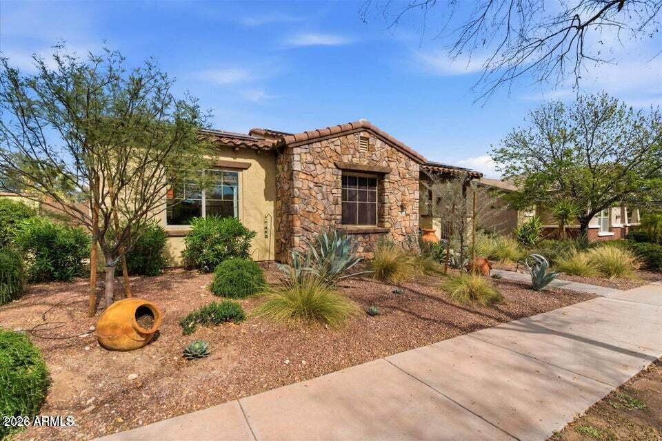 Welcome to Verrado living at its best. This beautifully upgraded 4-bedroom, 3.5-bath home offers a flexible floorplan with a main-level primary suite, private guest accommodations, office/den, and spacious upstairs loft. Designed for comfort and entertaining, the home features bamboo wood flooring, soaring ceilings, a gas fireplace, granite countertops, stainless appliances, and inviting indoor/outdoor living spaces. Recent upgrades include a new HVAC system, tankless water heater, solar panels, fresh interior/exterior paint, and newer refrigerator. Enjoy a private backyard retreat with extended pavers, covered patios, fountain, artificial turf, and heated spa, all near Verrado parks, golf, dining, schools, trails, and Main Street.