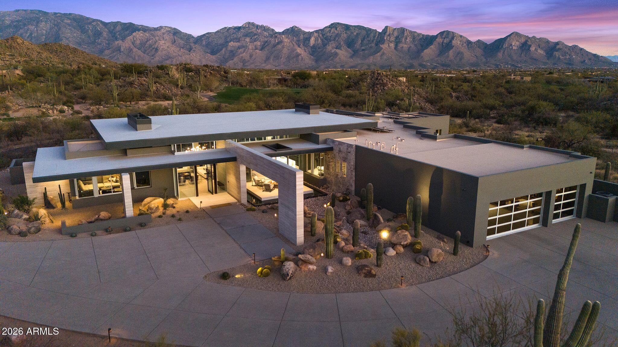 Fully turnkey and sold furnished as presented, The Reflectory is a luxury desert modern estate in guard-gated Stone Canyon, Oro Valley, Arizona - offering immediate enjoyment without the time or complexity of custom construction. Designed by acclaimed architect Ron Robinette, AIA, this 5,247 sq ft single-level residence (built 2024) rests on 1.005 acres with panoramic Santa Catalina and Tortolita Mountain views. Commercial-grade steel frame and CMU construction, expansive Fleetwood glass walls, and imported Italian porcelain flooring establish enduring architectural integrity. Four en-suite bedrooms plus a lounge/den are supported by four full and two half baths. Custom German Eggersmann cabinetry anchors the kitchen, centered around a 14-foot underlit waterfall island and complemented by a Sub-Zero, Wolf, and Miele appliance suite within a three-zone culinary layout designed for both daily living and elevated entertaining. Indoor-outdoor living unfolds to a front reflecting pond terrace and rear infinity-edge pool and spa, outdoor kitchen, and glass viewing deck. All designer and collectible furnishings convey. Residents enjoy The Stone Canyon Club's private championship golf and fitness amenities, while Tucson's mild winters, Canyon Ranch, Miraval, and UNESCO culinary distinction frame a setting defined by light, space, and discretion - an exceptional backdrop for immediate ownership and the life you choose to step into here.