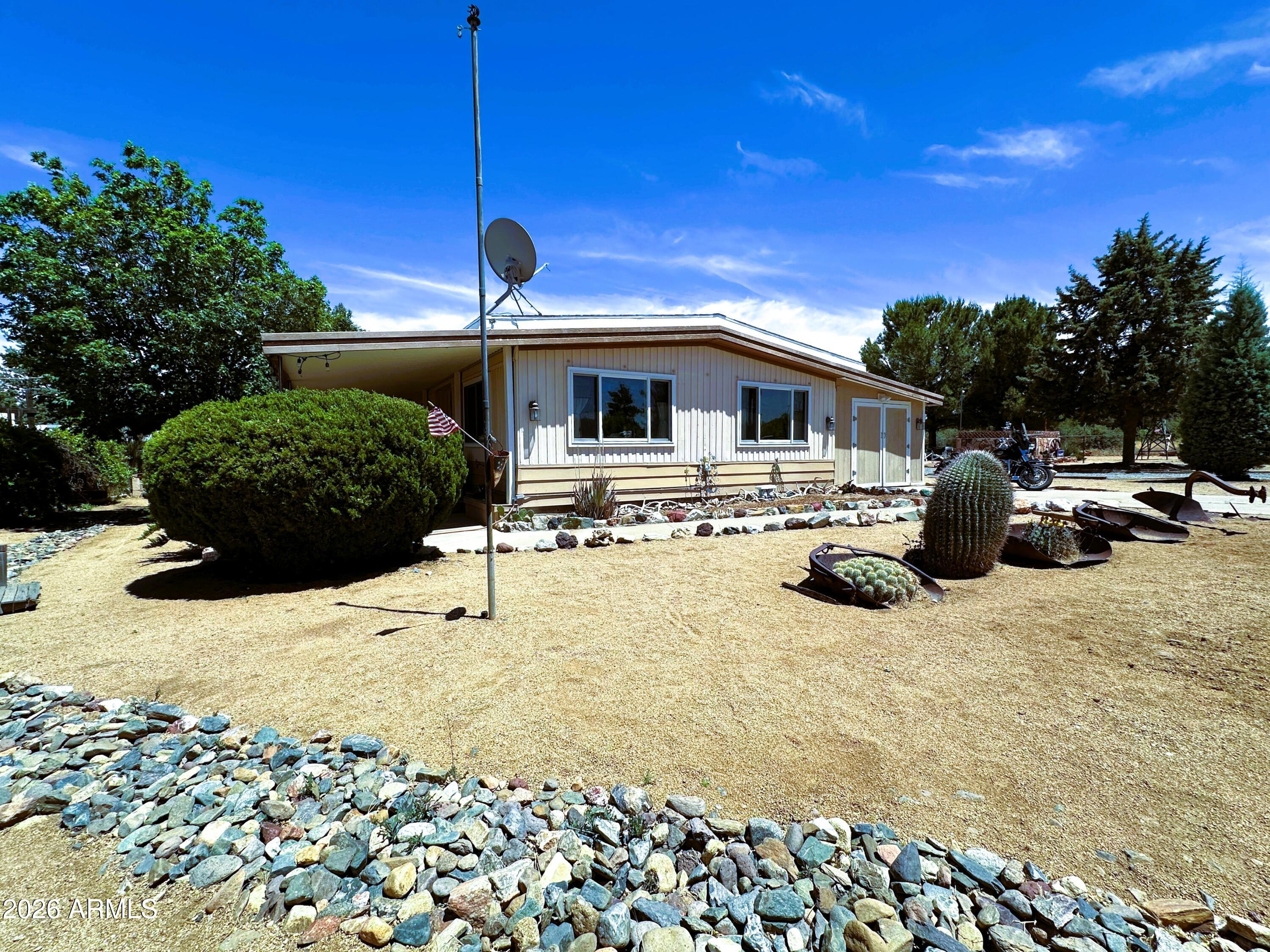 This beautifully landscaped property, with a 2 bedroom, 2 bath doublewide home, is located on a little under a 1/2 acre.  The property features a well maintained,1,248 sq.ft, home, with an open floor plan.  This home has a unique feature that has kept this home in excellent condition, an additional roof built over the home to protect the inside from any water damage or leaks. 
The property has it all... an RV Gate, RV hook ups, an attached 220V insulated workshop, extra storage, two outside storage sheds, a framed in garden space (13 X 24 ft: See Pictures), a small animal coop, a large pear tree that bears a mighty harvest come July and August, huge pines, and a gathering place for great evenings around the fire.  New double paned windows were installed in the living room and in the storage and workshop areas.  A new 1000-gallon septic tank and leach field were installed in 2016. Come and enjoy the coolness and peacefulness of Cordes Lakes, located within easy commutes to Phoenix, Prescott, and to the north and beyond.