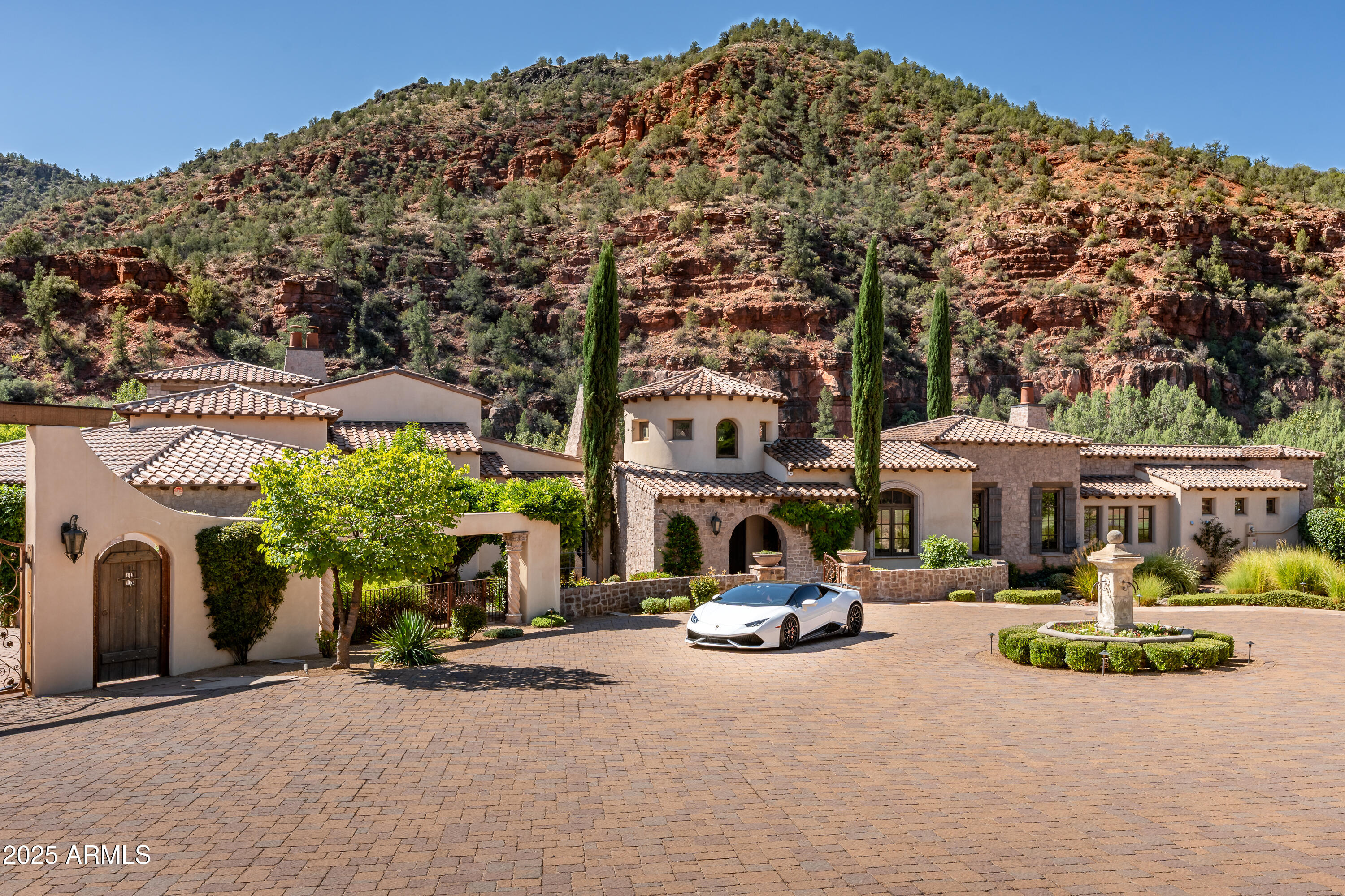 Vivi la  vita al megliore! Live your life to the fullest! Imagine if Old World Tuscan charm met the magical energy of Sedona, Arizona—welcome to Eagle Mountain Ranch, your private sanctuary within a gated haven where you can rejuvenate, celebrate, and embrace La Vita Bella.
Spanning ten contiguous parcels across 57+ pristine acres, this extraordinary estate offers 1,700 feet of Oak Creek frontage, a producing vineyard yielding hundreds of gallons of red Zinfandel grapes each year, plus a peach grove and apple orchard—all nurtured by a fully automated irrigation system. Some acreage carries agricultural zoning, equating to substantial property tax savings, while an owned 23KW solar power system brings modern efficiency to this timeless estate. Lounge on the sandy beach by day, gather around the firepit under starry skies by night, or wander into acres of lush meadow backed by National Forest, where the only audience for your song is nature itself. 

Outdoor living is elevated with enchanting water features, glowing braziers, a pond, two fireplaces, a 700+ gallon in-ground jacuzzi tub, and even a cigar room, all set against Sedona's iconic red rock backdrop.

The majestic main residence, one of only five Tuscan-inspired masterpieces, was reimagined with over a million dollars in renovations (2016). Driving through the gates, you enter another world....the circular entry greets you with Venetian plaster finishes and transports you straight to the Italian Riviera. At its heart, the great room features a fireplace and expansive pocket sliding doors remote-controlled to seamlessly blend indoor and outdoor living. The chef's kitchen dazzles with Subzero, Wolfe, and Viking appliances, dual dishwashers, warming drawer, convection ovens, prep sink, and a nearby butler's pantry. A full bar, complete with double kegerator, and Scotsman ice maker, is perfect for toasting milestones or enjoying an intimate nightcap.

Entertain grandly in the formal dining room with its dramatic arched stone entry, illuminated art niches, and dual wine cabinets storing up to 500 bottles. 

Retreat to the primary suite, where a cozy fireplace, sweeping views, and a bathroom draped in Arabescato marble create an atmosphere of pure indulgence. A chandelier glows over the soaking tub, while double doors open to the outdoor hot tub and views beyond. The pièce de résistance: an expansive closet fit for the most devoted shoe collector. A private office with built-in bookshelves hides a secret room, and two additional en-suite bedrooms ensure guest comfort and privacy. Throughout the home, a Crestron sound and light system sets the perfect ambiance.

Beyond the residence, an enormous climate-controlled four-car garage provides ample room for your tools and toys. Two charming guest homes, a rustic barn, and two historic red rock storage buildings expand the estate's versatility.

330 Eagle Mountain Ranch Road is more than a property it's an experience. Awe-inspiring to see, indescribable to feel, and waiting for the next chapter of its remarkable story.