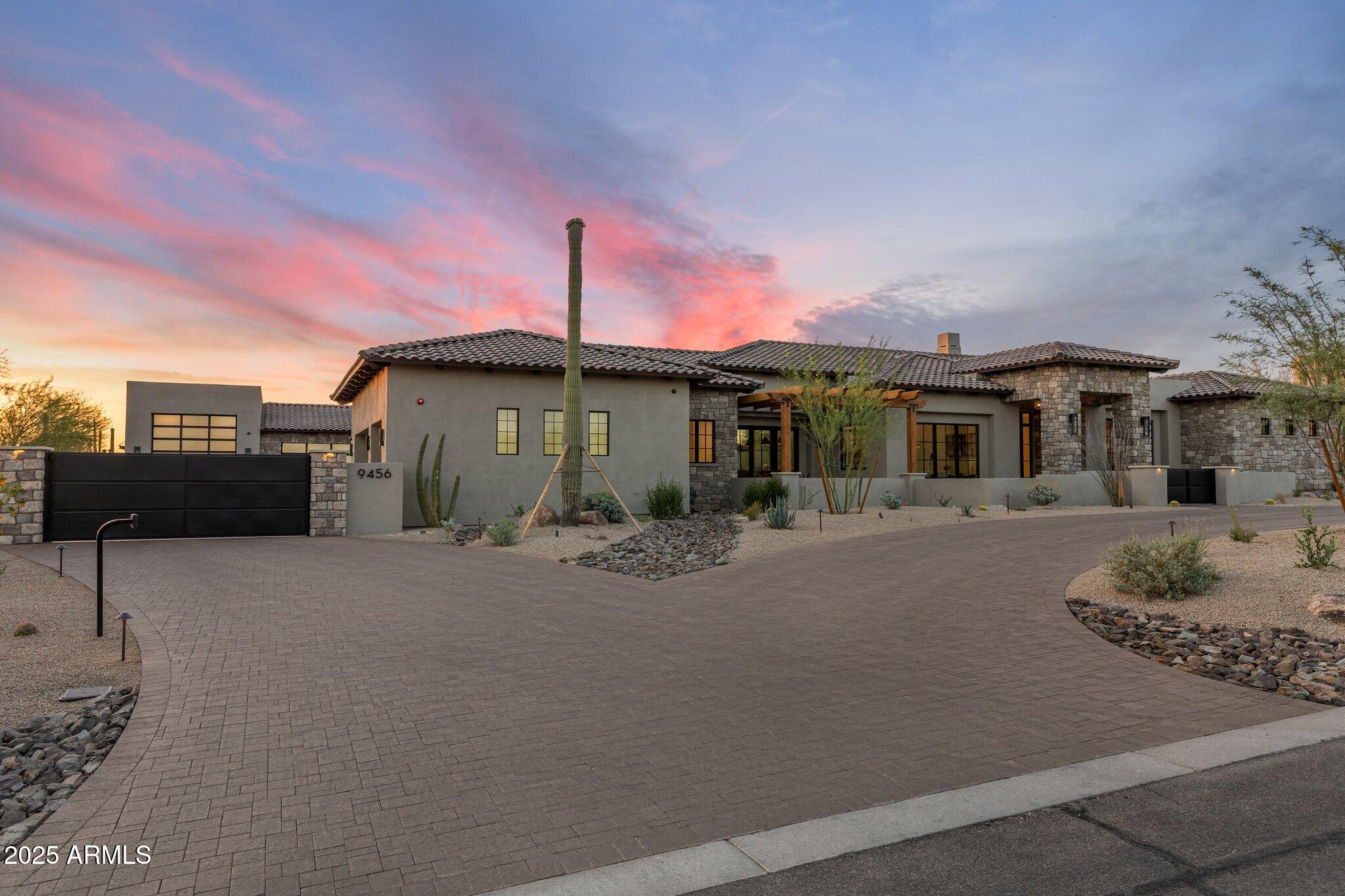 Welcome to this exquisite newly completed residence where timeless design meets modern luxury. The chef's kitchen is a showstopper—featuring double leathered quartzite islands, Wolf gas range and double ovens, built in fridge/freezer, Woodcrest Custom Cabinetry, dual dishwashers, wine cooler, built in drawer microwave and a pass through window that seamlessly connects to the expansive outdoor kitchen. The great room impresses with soaring wood-beamed ceilings, European white oak floors, a stunning fireplace wall with built in shelves, and dual multi-slide doors that create true indoor/outdoor living. Step outside to your private desert retreat with a heated pool and spa, custom outdoor kitchen with Danver outdoor cabinetry, fireplace, covered patio with tile pavers, fire pit, and multiple lounge areas all framed by breathtaking desert and mountain views. Inside, enjoy thoughtful touches throughout, including custom lighting and plumbing fixtures, a dedicated office, a spa-inspired primary suite with freestanding tub and multi-fixture shower, and a spacious laundry room. Car enthusiasts and hobbyists will love the attached 3-car garage PLUS a massive 1,890 sq ft temperature-controlled RV garage with an additional 2-car bay and bonus flex room ideal for a gym, guest suite, or workshop. This home truly has it all: luxury, function, and unparalleled style.