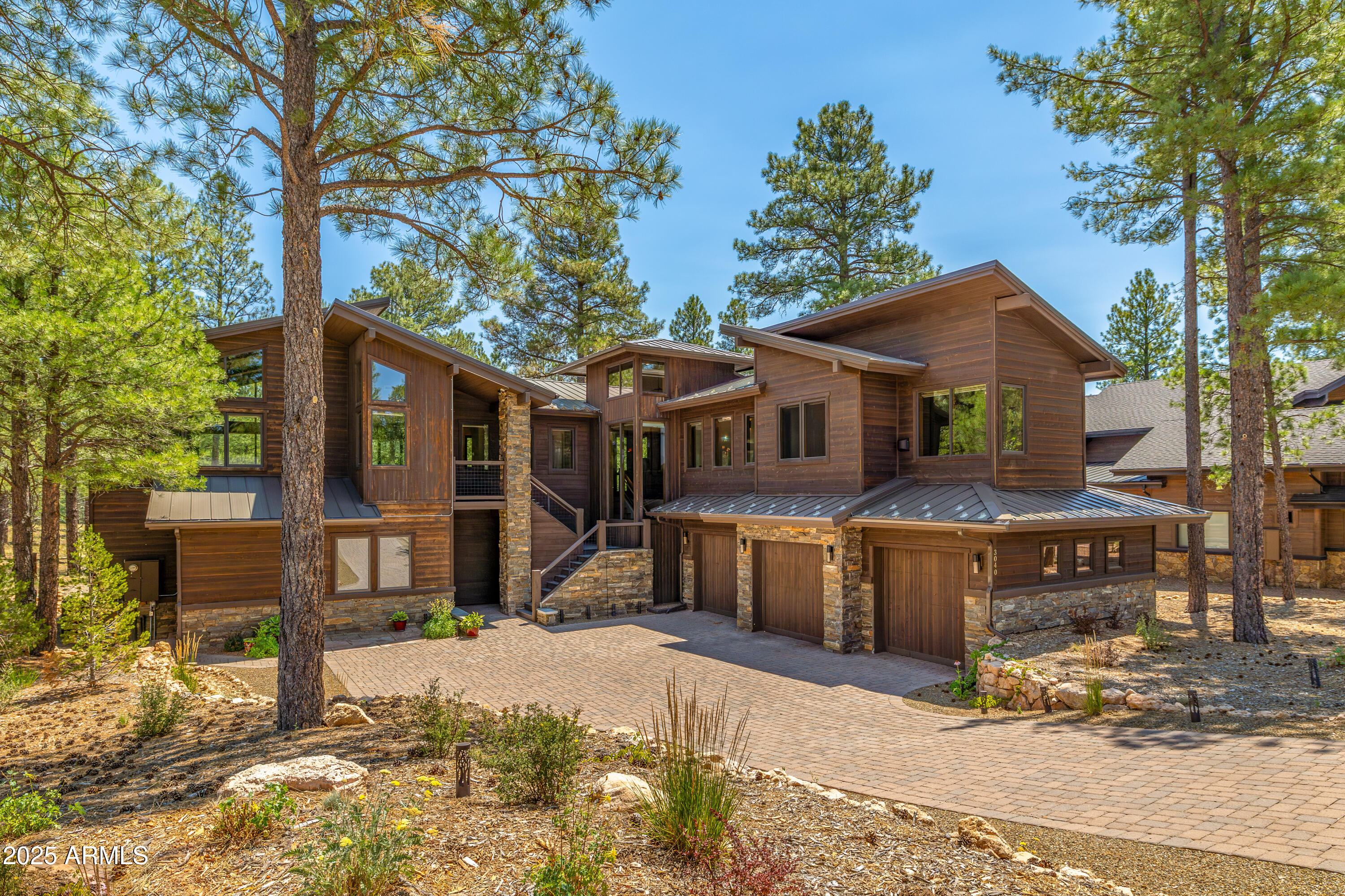 Nestled within the prestigious Pine Canyon community, this exquisite 3,832 sq ft single-family residence offers the perfect blend of refined elegance and natural beauty. Featuring 3 bedrooms, 4.5 baths, two primary suites, a dedicated den/office, and a 3-car garage, this home backs directly to the Coconino National Forest, providing unmatched privacy and year-round scenery. Step inside to an open, airy floor plan with soaring ceilings, expansive windows framing forest views, and a striking floor-to-ceiling fireplace. The chef's kitchen boasts premium appliances, open shelving, a large center island, and a walk-in pantry concealed behind a custom barn doorideal for both everyday living and entertaining.
Two luxurious primary suites offer spa-like baths and generous walk-in closets, creating private retreats for owners and guests alike. Every additional bedroom is generously sized with its own ensuite, ensuring comfort and privacy for all.
Retreat to the serene covered deck with its own stone fireplace, where you can relax and enjoy the tranquil forest backdrop. From thoughtful architectural details to a seamless indoor-outdoor connection, this home captures the essence of luxury mountain living at its finest.