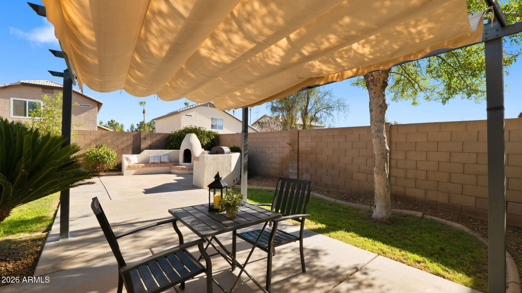 Welcome to a perfect blend of comfort, convenience, and Arizona living. This inviting home greets you with soaring vaulted ceilings & elegant travertine tile floors. The eat-in kitchen opens seamlessly to the bright living room, creating the perfect space for gathering with family & friends. A sliding glass door leads to your private backyard retreat, designed for year-round enjoyment. The split floor plan offers privacy, with the primary suite separate from the guest bedrooms. The spacious primary bedroom features a charming bay window, while the ensuite bath includes a soaking tub & walk-in closet. Step outside to an entertainer's dream backyard complete with a built-in BBQ, authentic adobe-style fireplace, cozy seating areas, & a large grassy yard perfect for play, pets, or relaxing. Conveniently located just minutes from Westgate Entertainment District, State Farm Stadium, Desert Diamond Arena, premier shopping, restaurants, and easy access to Loop 101, this home offers the perfect blend of comfort, convenience, and Arizona outdoor living.