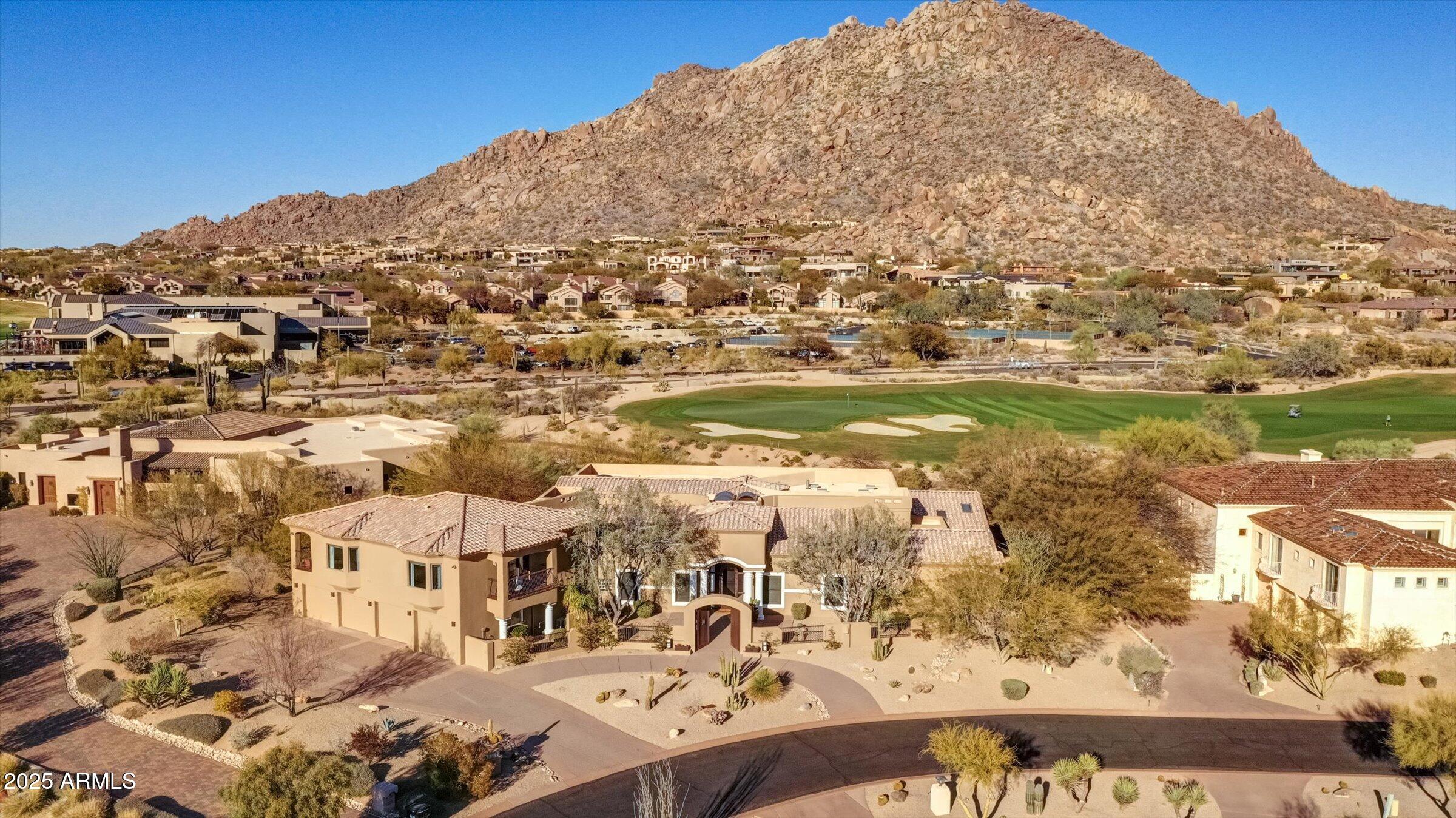 Troon Golf course Estate w/ unobstructed views of Troon Mountain, the 18th Green of private Troon CC,  Pinnacle Peak & captivating city lights with guard gated access. This stunning home features First-Floor Primary bedroom, open kitchen, Great room,  office and private den & 2 additional ensuite bedrooms downstairs & 2 large ensuite bedrooms upstairs. Natural stone, hardwood, travertine floors adorn this 7000+ sq/ft home that lives comfortably w/ 2 large rooms upstairs and a total of 5 fireplaces throughout, pool bath, 4 car garage, 1,000+ bottle wine cellar. Backyard oasis w/ large-covered patio, private pool, fire pits & is perfect place to watch the sunsets on the Mountain & the golf course!  Enjoy this Troon Village prestigious community, almost walking distance to the country club!