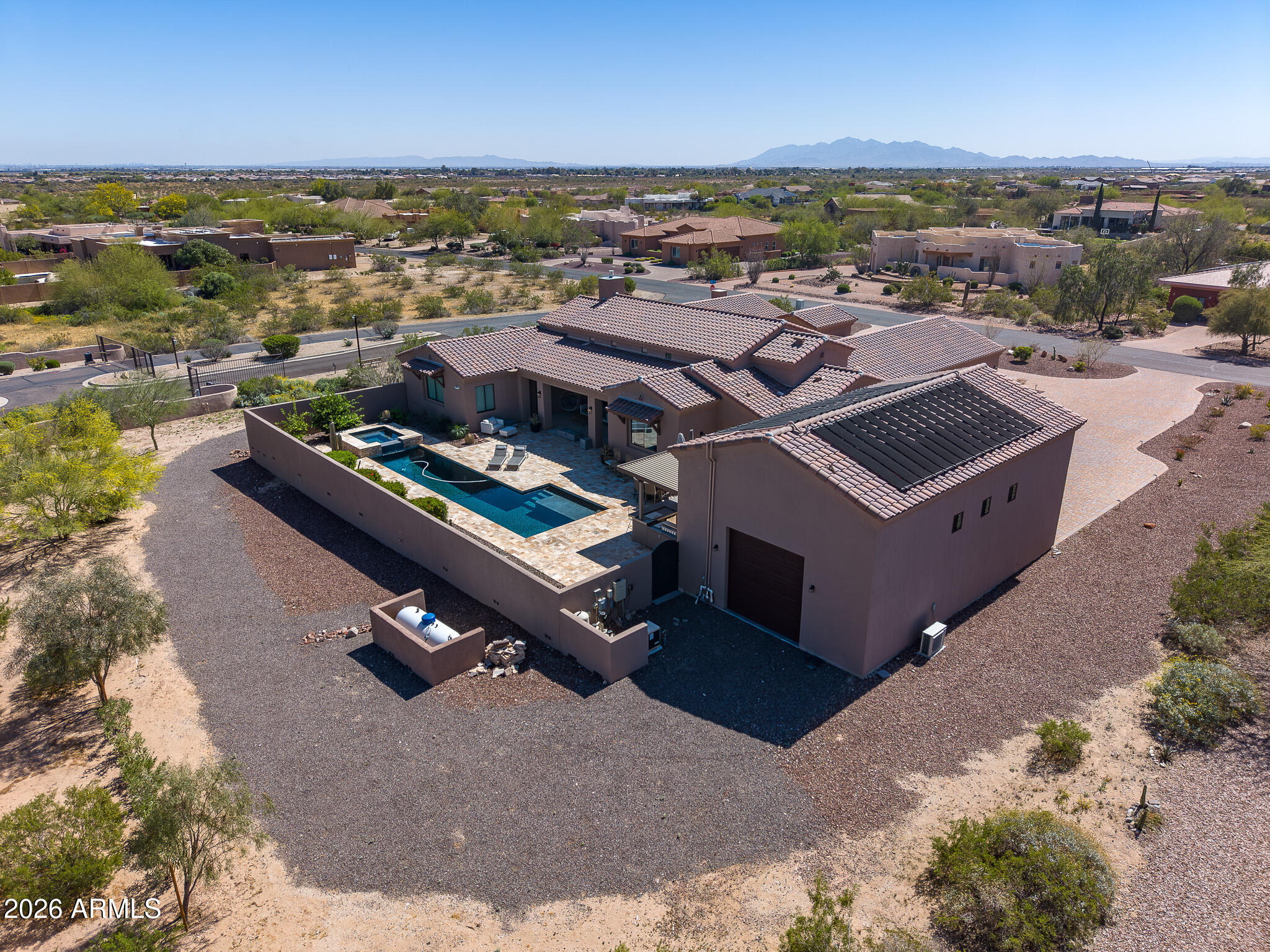 Welcome to a gorgeous home nestled within the heart of the Arizona desert. This custom home, built in 2021, sits on a 41,274 sf lot within the gated community of Sonoran Ridge Estates. This home is conveniently located 4.8 miles to the Loop 303 and 7 miles to a newly developed entertainment district offering Costco, wonderful dining and shopping! Apart from a great location, this home resides in an A+ school district with elementary, charter and high schools within 2.3 miles. This special home features four large bedrooms and four and a half luxury baths, including three en-suite bedrooms, there's ample space for both family and guests. The kitchen is a masterpiece, featuring a beautiful island, custom cabinets and GE Monogram appliances, all illuminated by an abundance of natural light... The home is spacious with tasteful tile flooring throughout, creating a seamless flow. The dining room is a delightful space for gathering, and a butler's pantry complete with bar and wine fridge is perfect for entertaining.

The primary suite is a true retreat with door leading to the patio and an expansive walk-in closet. The bathroom is a sanctuary with a freestanding tub and a shower with intricate tile work. This tile work carries through to the thoughtfully designed backsplashes and a striking fireplace in the living area. The connect between indoor and outdoor living is seamless, thanks to 20' massive sliding doors that lead to the backyard retreat. A solar heated, sparkling pebble tech pool with travertine tile, is perfect for relaxation. An outdoor kitchen, nestled under a pergola, is perfect for gathering with family and friends.

There is a climate controlled, detached RV garage measuring 23'x44' with epoxy flooring perfect for car collectors or those with larger vehicles. Additionally, there is a three-car garage with the same pristine epoxy flooring, custom cabinetry and ceiling fans to keep cool.

Located at the base of the White Tank mountains, the views are beautiful! This home has many gorgeous features/upgrades and so much to offer, you don't want to miss it!!