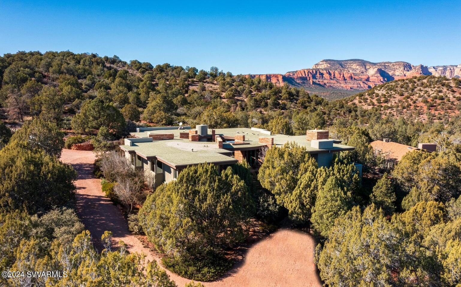 Signature Design Group home on 2.5 acres bordering National Forest, with unsurpassed panoramic Red Rock Views and ultimate privacy. -
Securely located on the cal-du-sac of a high-end gated community this extremely private home is set high into the hillside, perfectly built to be part of the terrain and toward big northern and eastern views from Summit, Chimney Rock, Thunder Mountain and Lizard Head to Boynton Canyon and Bear Mountain. - The main house with living room open to dining and high-end kitchen - all three built around a large three-sided fireplace - features the master bedroom suite, a bonus room currently used as gym, and a powder room. The soothing sound of a water feature outside the master bedroom attracts a large variety of wildlife.  Connected by a covered circular walk way, the casita offers two large guest bedrooms, a bath and a bonus room. One of the bedrooms and the bonus room are currently used as offices. -
Both main house and casita are built around an enchanted round court yard with wood burning fire place, outdoor kitchen, spa and a large view window. The well designed pond with waterfall contributes to the ambiance. 
Large windows and multiple outdoor sitting areas allow indoors and outdoor to blend seamlessly and facilitate the all year round indoor-outdoor Sedona lifestyle. 
Observe wildlife from the privacy of your home, watch dramatic sunrises and sunsets reflected on the Red Rocks, curl up in front of one of the fireplaces, delight in Sedona's starry nights while soaking in the hot tub, listen to the sound of running water, entertain friends or start hiking and biking endless miles of trails from your home.-
In spite of living next to National Forest it is only a short drive to restaurants, shops, entertainment and all amenities of town. Just a few minutes drive from the Enchantment Resort with its world renowned luxury Spa Miiamo and the Seven Canyons private golf club. 
Single level with only 2 steps down to living room and from garage.
Easy to take care of landscaping and lots of storage space.
Plenty of room for a pool.
No vacation rentals possible.