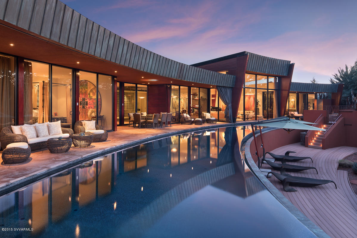 Sedona Living at its finest in this flawlessly designed and finished home bordering National Forest. Securely located in a small gated community of high end estates it is surrounded by Nature, imposing Red Rocks and hiking trails. Designed by NY based firm Sanba Int. and local architects Design Group, this inspiring composition of glass, metal and wood high lights artistic clean and exciting lines without compromising comfort and livability. - Overlooking the 85 ft. negative edge pool, walls of glass open to some of the most dramatic and sweeping Red Rock views Sedona has to offer - from Lizard Head and Thunder mountain, to world famous Boynton Canyon, Bear Mountain and Cockscomb. Finishes are museum quality throughout. - The Foyer opens to a large open glass Atrium that allows Nature to enter the house while large patio spaces wrap around the half moon shaped pool, facilitating the ideal Sedona indoor/outdoor lifestyle. The home is located close to Enchantment Resort's Luxury Spa Miiamo and the Seven Canyons Private Golf Club. -
In addition to the large master suite with private spa patio and outdoor shower, there are three guest suites, a state of the art theater for movies and audio concerts, an extra room with attached powder room and shower currently used as fitness studio, an additional office and a gorgeous meditation room. Two climate controlled garages fit 4+ cars and there are plenty of storage spaces - all climate controlled.  
For more detail see below.

LIST OF ROOMS AND AMENITIES:

 * Formal entrance with over sized custom door in mahogany with acrylic inserts, curved glass blocks enclosure around door.
 * Kitchen completely fitted with Italian made cabinets (Varenna by Poliform) in cherry wood and incorporating a cooking island, a breakfast area and a sky-lighted circular pantry.Appliances include: Subzero refrigerator, subzero freezer, Wolf six-burner cook-top, Astra kitchen hood, two Bosch ovens, two dishwashers (one from Miele and one from Bosch), an ice-maker from Subzero, two sinks with Grohe kitchen faucets and drink refrigerator under counter.
Kitchen backsplash in mosaic tiles, countertops in Brazilian granite.
 * Master bedroom, featuring an Italian closet system in cherry wood and sandblasted glass (by Poliform), facing a private terrace with access to the swimming pool and to a custom outdoor shower and whirlpool tub, metal-glass art screens by Madak.
 * Master bath 2009, Vanity and integral sinks are glass by Coyote Glass, custom cabinets with juniper/maple combination by Mike Bartell, floors slate, shower tile by Ann Sachs, plaster walls and stained glass.
 * Laundry room, furnished with European custom cabinets, Bosch washer and dryer. 
 * Formal dining room, located between the internal garden and the outdoor terrace.
* Atrium, enclosed by oversized glass, featuring a water feature.
 * Theater, state of the art for both movies and concerts/audio, McIntosh sound system, Aerial speaker system, leather seating by Cineak, custom tables designed by Design Group-fabricated by Glendon Good, plaster walls, flagstone flooring, bar stools Saporiti Italia.
 * Meditation room, round with plaster walls, dome, water feature around room.
 * Fitness studio, with powder room and separate shower, slate floor.
 * Office, slate floor.
 * Service entrance, for easy access from garage/carport. 
 * Guest's quarters, with oversized bedrooms, full baths, Italian custom closet system and custom cabinetry by Rasen.
 * Storage room, with easy access from garage, carport and service entrance, climate controlled.
 * Basement, easily accessible from an outside staircase, incorporating the HVAC mechanical system, the pool-whirlpool equipment, a wine cellar and additional storage space.
* Outdoor terrace, (for a total area of 2,500 sq./ft.), paved in Arizona flagstone and partially covered for sun and rain protection, with a space for outdoor dining, furnished with stainless steel barbecue and hood.
 * Negative edge sale water swimming-pool, (85' long), reflecting the curved shape of the house, heated and lighted, self cleaning system, water provided by reverse osmosis system.
 * RTI home automation system, light and programmed settings, surround sound controls in all areas, motorized shades and blinds, automated TV-lift, each bedroom has own satellite box, settings for each room-private.
 * 5 â€“ Zone-HVAC
 * 3 Osmosis systems, all water, including pool, is reverse osmosis.
 * The house has been superbly soundproofed, vertically and horizontally.
 * Custom mahogany siding has been installed on the east fassade and on the garage door.
 * The lower deck has been fabricated with trex, a material that allowed bending into a curved shape.
 * Custom made copper has been installed and patina-treated in all the overhanging fascias of the roof and on top of the living room roof. 
 * All windows are double-glazed low-e.
 * The wood floor is African dousse' Linea, purchased in New York from Pianeta Legno. The installation follows, in each room, the radial pattern of the house. 
 * All bathrooms, pantry and gallery walls have been covered with Venetian stucco.
 * Guestroom baths include Italian Catalano sinks, French Duravit freestanding bathtub, and Kohler faucets in chrome-finish. 
 * All passage doors, inclusive of hardware, have been imported from Italy and made by Lualdi.