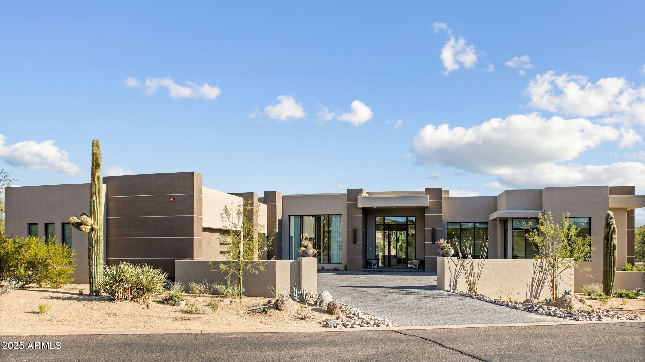 GOLF MEMBERSHIP AVAILABLE | FULLY FURNISHED TURNKEY HOME. This dramatic desert modern residence is ideally positioned just inside the guard-gated entrance of Desert Mountain, offering a rare blend of architectural sophistication and seamless indoor-outdoor living. Designed to embrace its surroundings, the home features expansive sliding glass doors that invite the desert landscape into the living spaces—perfect for both everyday living and elevated entertaining.
Furnished in collaboration with Jamie Rose Interiors, this home is offered fully furnished and turnkey, showcasing a curated collection of refined finishes and elegant design details throughout. An open-concept floor plan unfolds into expansive living areas, anchored by a chef's kitchen that serves as the heart of the home. Outfitted with top-of-the-line Wolf and Sub-Zero appliances, including an icemaker and built-in Miele coffee maker, the kitchen is complemented by multiple beverage refrigerators thoughtfully placed throughout the residence. Wine enthusiasts will appreciate the custom wine cellar, along with additional temperature-controlled storage located within the pantry.
A state-of-the-art Crestron home automation system provides effortless control of audio, televisions, security, pool and spa, and surveillance cameras. Notable upgrades include automated window treatments in the primary suite, tinted windows for sun protection, bar backlighting, and owned solar panels for enhanced energy efficiency.
Guest accommodations are equally impressive, featuring three generously sized guest suites, including a private casita with its own living area and kitchenoffering exceptional privacy and comfort. Outdoor living spaces rival a private resort, with a sparkling pool and spa, full outdoor kitchen with refrigerator, sink, and Wolf BBQ, and multiple seating areas ideal for entertaining or quiet relaxation.
Crowning the home is a rooftop view deck offering panoramic vistas of the Renegade Golf Course's 17th hole, dramatic desert sunsets, and sweeping mountain viewsan extraordinary finishing touch to this exceptional Desert Mountain retreat.