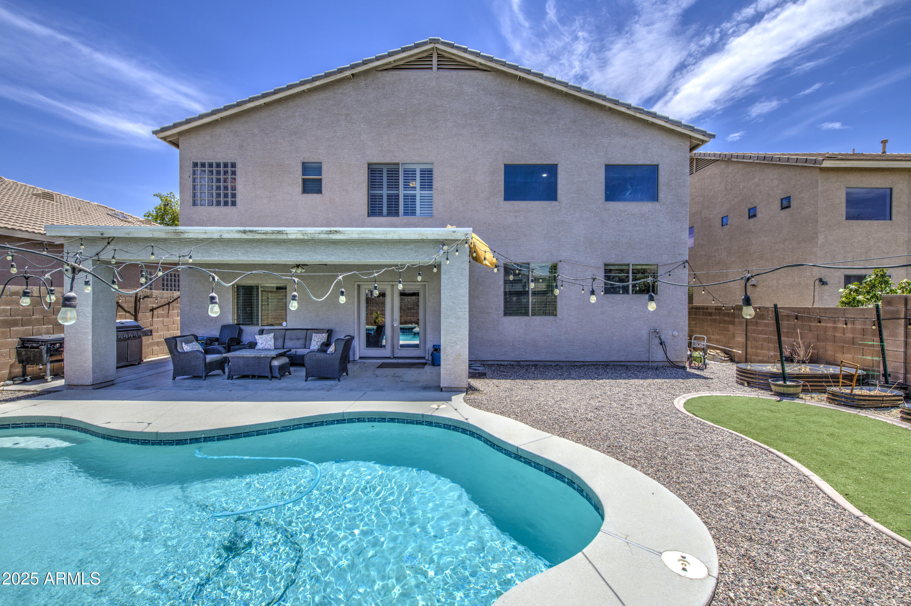 Experience elegance in this beautifully upgraded home, perfect for both living and entertaining. Sleek 24x24 tile flooring flows throughout, while soaring 15+ ft ceilings in the kitchen and receiving room create an inviting, open atmosphere. The stylish kitchen is a chef's dream, complete with granite countertops, stainless steel appliances, and a convenient mini drink fridge. The family room boasts built-in surround speakers for exceptional entertainment and double doors that open into the backyard pool area. A spacious living room provides ample space for gatherings, and the backyard features a sparkling pool, perfect for enjoying warm Arizona days. Thoughtfully designed with both style and functionality, this home is ready to impress!