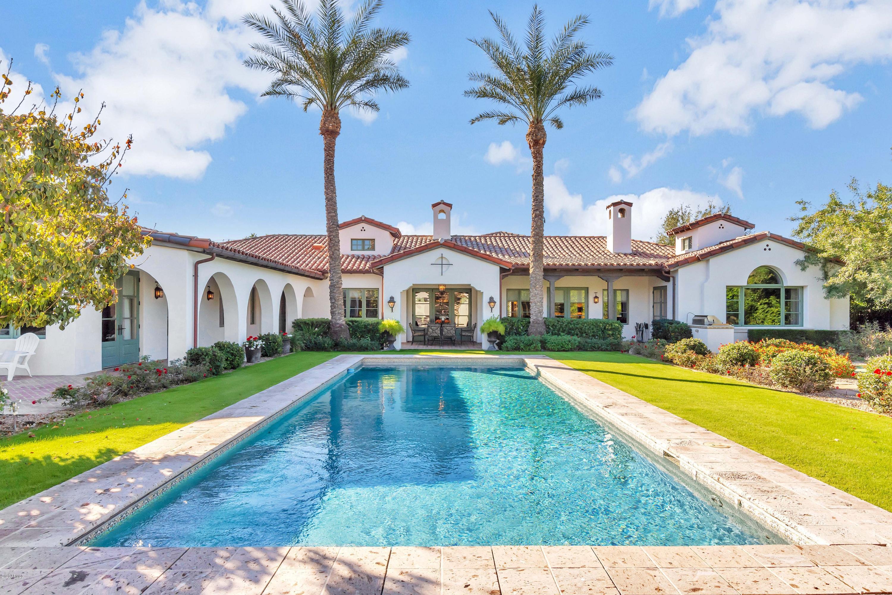 Located on the most coveted street in Arcadia, Exeter Boulevard, this stunning Spanish Revival home is simply breathtaking. Designed by award-winning Architect and valley native, Michael Higgins, the beautifully detailed architecture showcases elegant arches, tower-like chimneys, multiple courtyards, and breezeways. The gorgeous hand-painted tile murals throughout add touches of Spanish authenticity. Juxtaposed with a gorgeous smooth stucco exterior and a reclaimed brick courtyard entrance, you are greeted by Tudor style diamond glass double doors. Upon entry, the two-story foyer spills into gallery style hallways and welcoming formal dining space. The interiors by Bouton and Foley were meticulously designed with features of note including Paul Ferrante light fixtures, solid hand scraped wood floors, custom cabinetry with Bouvet hardware, stone counters, charming wall coverings, and intricate tile work throughout. The seamless split floor plan offers en-suite bedrooms, a designated office with tasteful millwork, a large game room with stunning mountain vistas, and a central great room. The large main suite offers panoramic views, an exquisite bathroom with detailed finishes, and large closets. The rear of the home captures views of Camelback mountain, a sixty-foot pool that reflects the image of the luxurious ramada inclusive of a full bathroom and outdoor shower. A putting green, lush lawn, expansive patios, and grilling station make entertaining al-fresco easy. The refined classic elegance punctuated by luxurious detail make this home simple perfection.