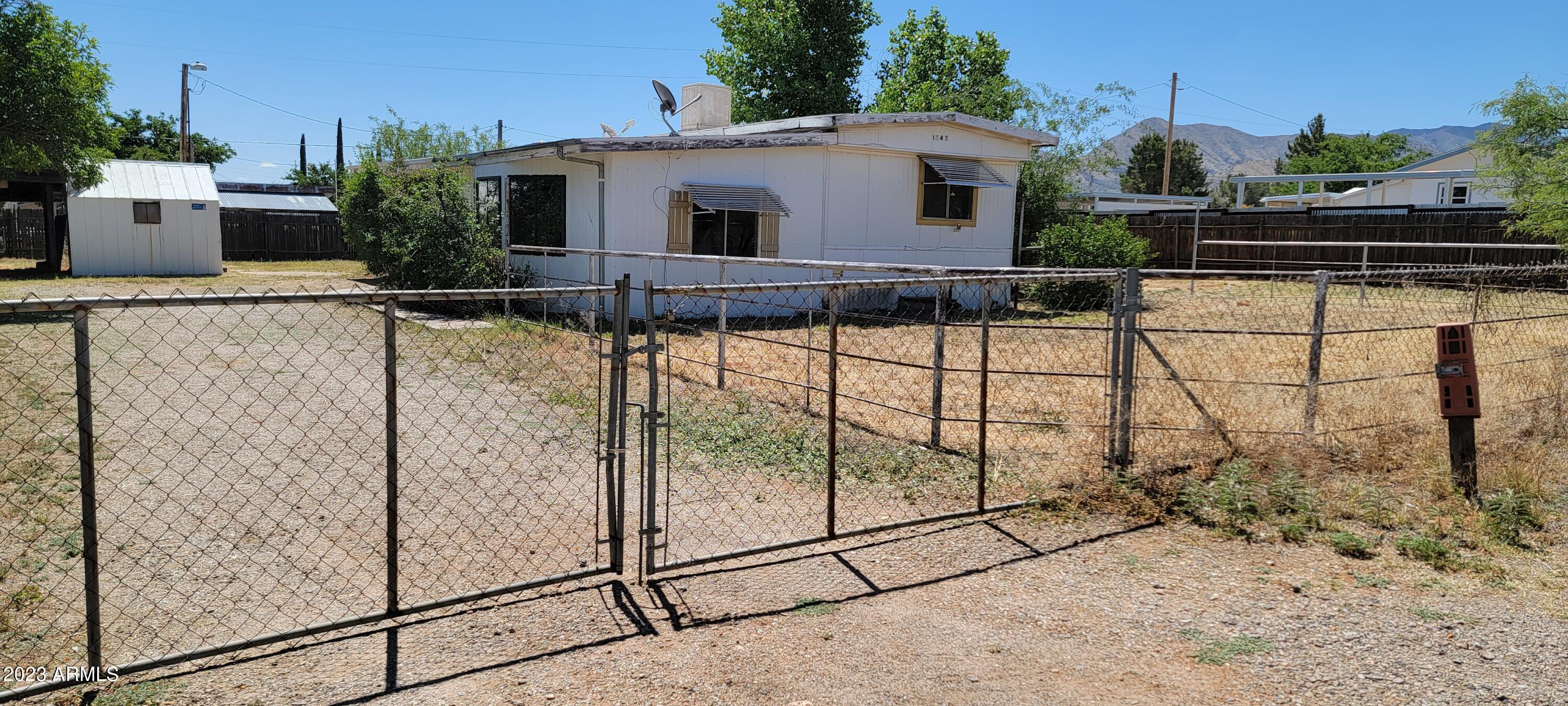 If you are looking for affordable housing, look no further! This cute home on a quiet street is just what you are looking for. There is a 1973 mobile home with a large add on. The square footage includes both. There is also a carport with a shed next to it for storage. There is an RV Gate as well. On the 2nd little lot included within the fence there is a trailer and a shed that provide extra storage. These will remain with the property. This is an AS IS sale.