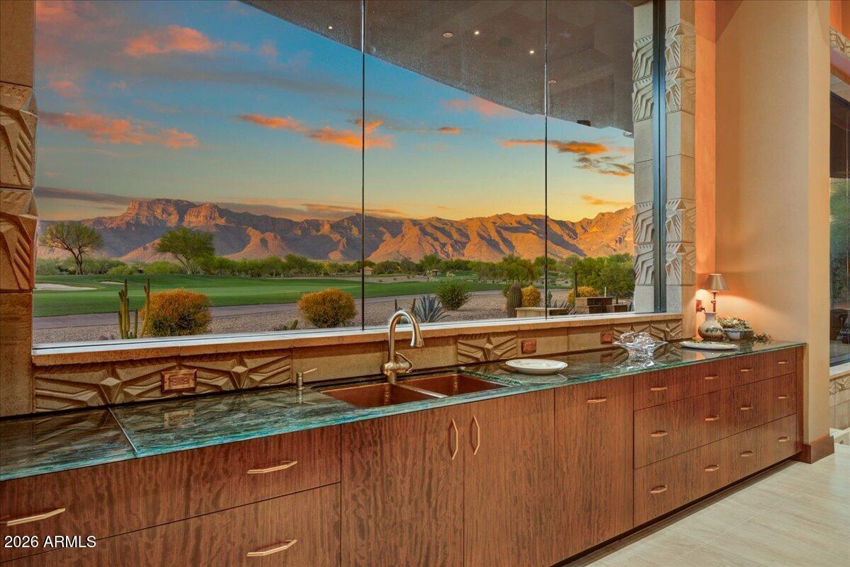 Exquisite one-of-a-kind contemporary home.  Prime location within beautiful Superstition Mountain Golf & Country Club. This extraordinary residence has expansive walls of glass showcasing panoramic golf course and mountain views while filling the home with natural light. The architecture is based on the famous Arizona Biltmore Hotel. Skillful design, soaring ceilings, and high-end finishes create a stunning environment for both entertaining and everyday living.  There are two fully-finished, temperature-controlled garages.  One can hold 6 cars while the other is an oversized 2-car garage that's currently used as a guest suite and could easily become a full casita.  The main house has 3 bedrooms and 5 baths. The bedrooms feature fireplaces and luxurious ensuite baths, providing resort-style retreats.  The gourmet kitchen - featuring premium appliances, ample counter space, and elegant cabinetry - is adjacent to spacious living and dining areas plus a 15-foot wet bar.  The dining area boasts temperature-controlled 350-bottle wine storage. Step outside to a spectacular desert setting where the golf patio and sitting area faces multiple fairways and a dramatic Superstition Mountain backdrop. Step outside the other direction to a full outdoor kitchen, large enclosed courtyard, and heated pool and spa graced by desert greenery and a beautiful two-sided fireplace.  Whether enjoying peaceful mornings, radiant Arizona sunsets, or gatherings under the stars, the outdoor spaces offer unmatched tranquility and privacy.  Residents often describe the community as the friendliest, most welcoming they've ever experienced.  Its two 18-hole Nicklaus-designed golf courses are complemented by excellent clubhouse dining, fitness facilities, tennis, pickle ball, bocce, and miles of scenic trails. Access to the community and private club (membership optional) is managed by 24/7 gatehouse attendants.  35 minutes to Phoenix Sky Harbor; 20 minutes to Mesa Gateway.  Buyer and/or buyer's agent to verify all pertinent information including square footage.