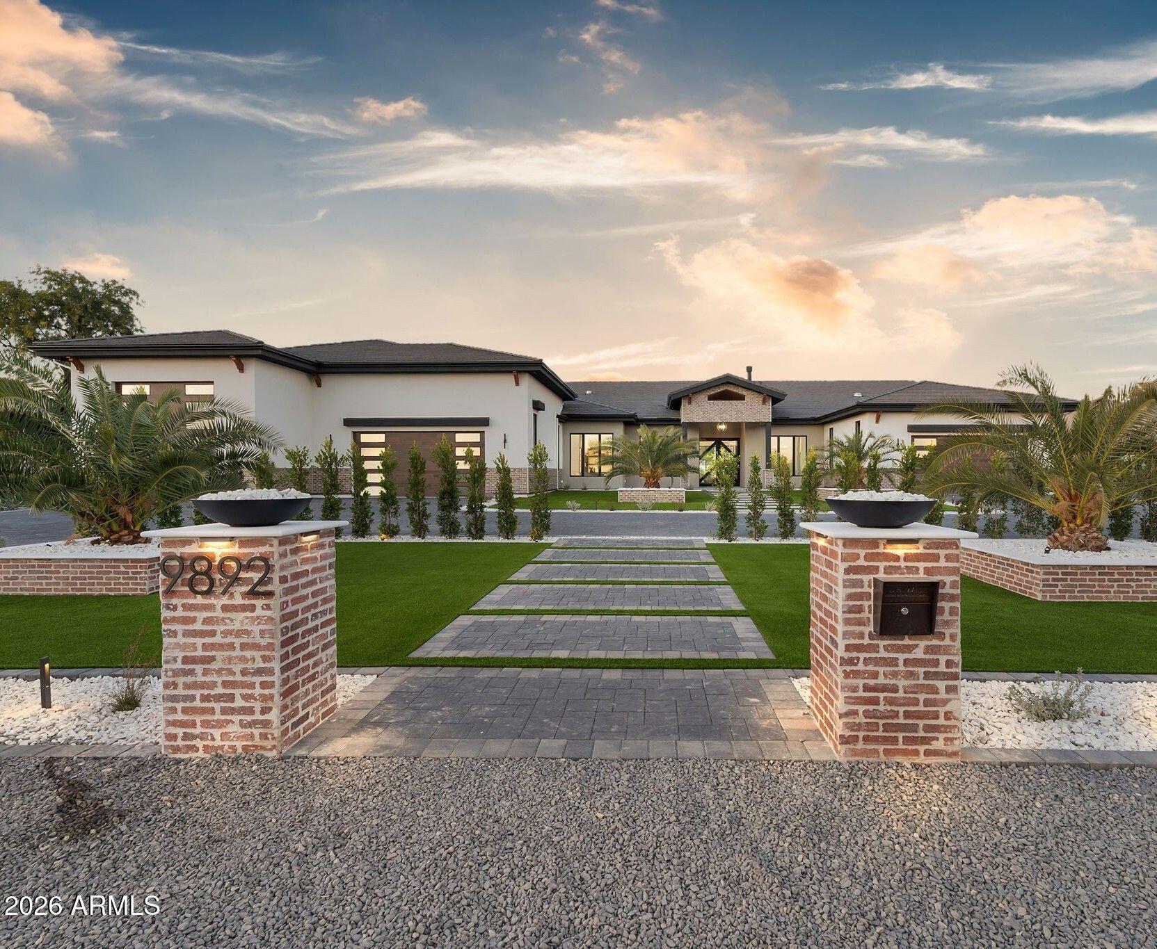 In the heart of Scottsdale's prestigious Cactus Corridor—an enclave revered for its rare large-lot serenity & timeless Sonoran beauty, this brand-new residence offers an exquisite expression of chic desert living on a generous 1.25-acre private lot. Here, warm contemporary modern meet clean architectural lines, softened by rich, organic textures, abundant natural light, and materials that celebrate the desert's quiet splendor, creating a home that feels both profoundly sophisticated and deeply inviting. The 7,930 sq ft master-split floorplan is  composed for privacy and flow—the primary suite, a tranquil sanctuary on one wing, provides secluded elegance, while secondary bedrooms and communal spaces reside on the opposite side, allowing effortless connection without compromise. Soaring ceilings with blackened exposed beams and subtle linear LED lighting introduce quiet drama, while wide-plank white oak wire-brushed engineered hardwood glides beneath foot, infusing every room with natural warmth and understated refinement. The chef's kitchen is the soul of the home: custom spiced oak cabinetry by Superior, are a sleek flat-panel design, crowned by luminous Perlato Taj Quartzite. A monumental central island with waterfall edges and integrated black bases anchors the space. Wolf and Sub-Zero appliances (with GE Profile in the butler's pantry and office) perform with quiet authority. Living areas revolve around a breathtaking Italian Marvel Fior Di Bosco porcelain slab fireplaceits intricate, marble-like veining a sculptural masterpiece that draws the eye and warms the spirit. Secondary baths and laundry maintain this refined harmony with Della Citrine Quartzcreamy elegance accented by subtle grey-goldand matching spiced oak cabinetry, elevated by frameless glass showers, oversized black-edged mirrors, and slender vertical LED sconces that evoke a private spa retreat. Fully pre-wired for whole-home audio, security cameras, and advanced AV, the home anticipates every modern need with seamless grace. The garage compound is a collector's haven: expansive climate-controlled bays (including attached RV space) and additional insulated storage, accommodating 8 cars normally or 12 with lifts. Beyond the glass walls, the backyard unfolds as a private oasis of natural beauty and refined leisure: expansive covered patios (3,000 sq ft of covered) transition effortlessly to clean neutral-grey hardscaping, leading to a lighted half-court basketball area, a regulation pickleball court with premium SportMaster surfacing, a pristine putting green, and a shimmering pool. Crisp white privacy walls, graceful palms, and sweeping McDowell Mountain vistas frame the scene, turning every gathering into an experience of pure desert serenity. Curated with the finest materials, intuitive technology, and expansive grounds that embrace both privacy and possibility, this 6-bedroom, 7.5-bath residence is a rare embodiment of chic desert living.. elegant, natural, and profoundly luxurious. Step into elegance that feels like home.