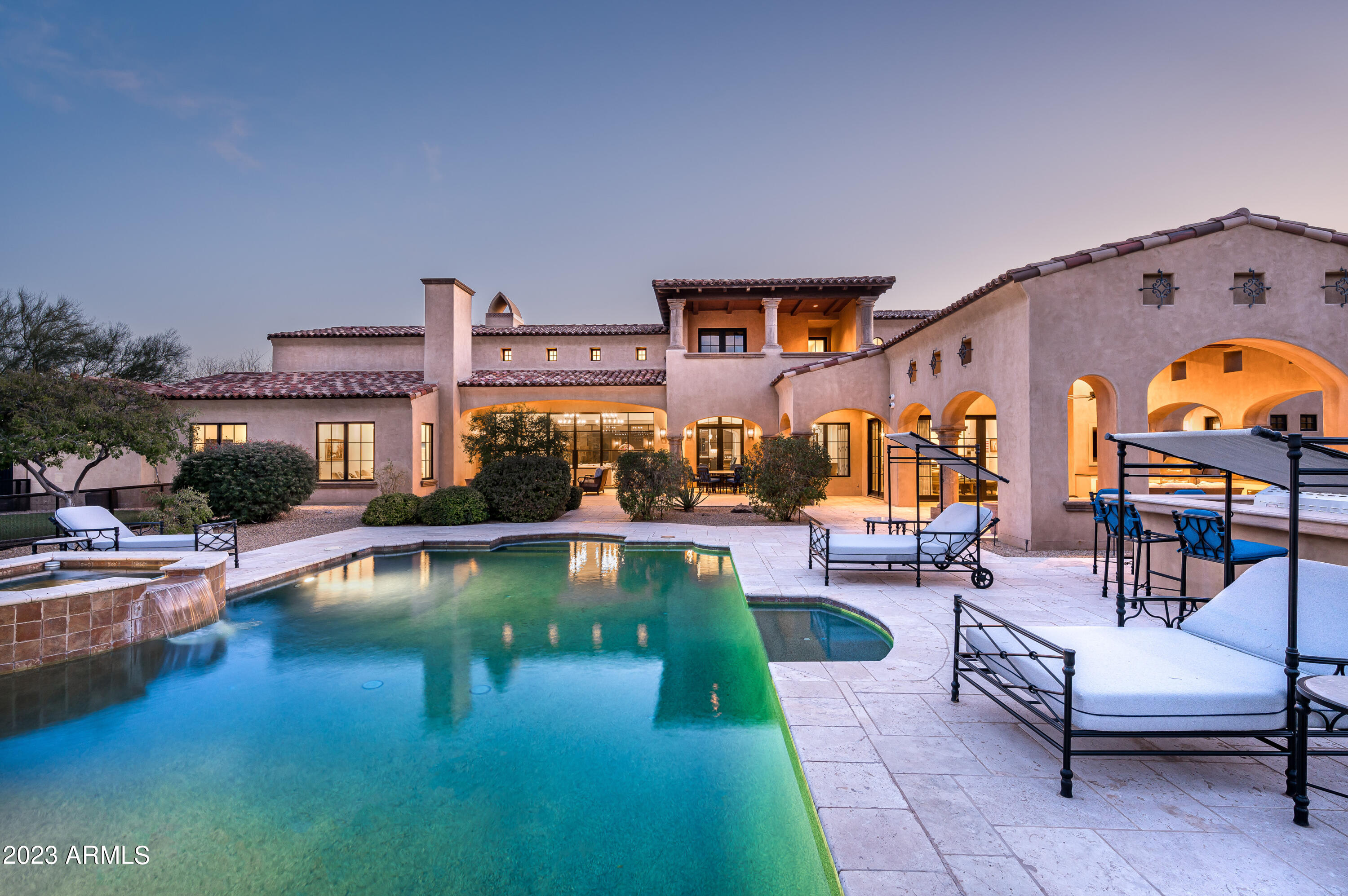 The best of Prado Estates.  Elegantly crafted and styled this Modern Spanish estate has been completely renovated by Mike Graham of American First Builders, exemplifying all that is modern and sophisticated.  Featuring large functional living spaces opening to sweeping mountain and city views on this rare, large 4.7-acre estate lot. Upon entering, a large private courtyard leads to a stunning entry with custom steel windows and doors throughout capturing views of Pinnacle Peak and distant mountain vistas.  Enjoy the open floor plan featuring a gourmet kitchen with double islands, a fully equipped butler's pantry and a welcoming great room with beamed ceiling detail and custom built ins.  The Primary suite and office are located in a private area of the home while the en suite guest rooms are all spacious with private bathrooms featuring customized detailed tile work throughout.
The massive 6 car garage, workshop and auto court make this home perfect for a collector or large family. A large two-story guesthouse includes two bedrooms and a private living area. Expansive resort like grounds featuring a private sport court/tennis court, putting green, custom outdoor kitchen with BBQ and pizza oven, heated pool and spa with room to add countless amenities. All located at the end of a quiet and private gated street. Prado Estates is convenient to multiple golf courses, hiking, shopping and restaurants in North Scottsdale. Truly the best of Arizona living!