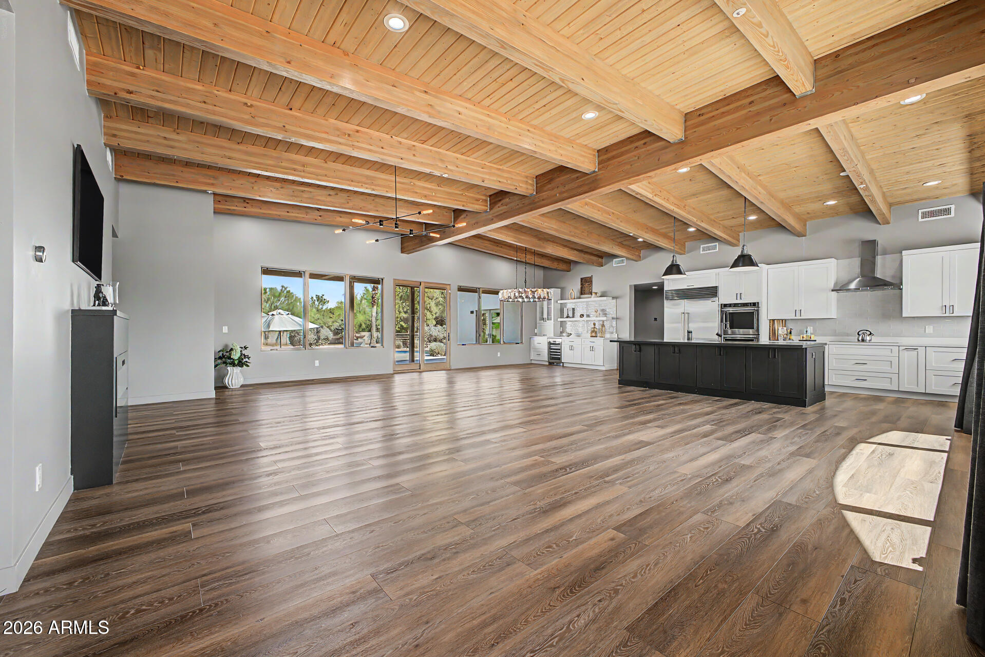 Experience elevated desert living in this exceptional Scottsdale estate, perfectly positioned on an expansive private lot with a circular driveway and impeccable curb appeal. Designed with luxury in mind, this stunning residence showcases high-end finishes throughout, ceilings accented with gorgeous rich wood beams, an immense amount of natural lighting coming through the large front and back windows, and a thoughtfully designed split floorplan offering ultimate privacy. Retreat to the lavish primary suite with a spa-inspired bath designed for relaxation and sophistication. Large, tiled shower with separate soaking tub, his and her sinks, and a primary walk-in closet that would be the envy of anyone who sees it. Both the primary bedroom and closet offer separate entrances to your backyard, and laundry is conveniently located both by the primary and secondary bedrooms. Two secondary bedrooms include their own en-suite bathroom with glass enclosed showers, providing comfort and convenience for family and guests alike, and all bedrooms have walk-in closets. The chef's kitchen features stunning custom white cabinetry and granite counters accented by a large island with black granite counter and cabinets, and stainless-steel appliances with built-in ovens. Your pantry is a room of its own with numerous shelves and separate sink for convenience. Added cabinetry with beverage cooler in your dinette area allows for a coffee bar, liquor display cabinet, and more. This seamlessly opens to your elegant living and entertaining spaces with fireplace. Enjoy movie nights in the theatre room, which also can be used as a dedicated home gym or office. Attached to the main home is an oversized four-car garage with epoxy flooring and in the backyard is a separate two-car garage accessible through the RV gate, which also leads to the expansive RV parking area. Enjoy breathtaking sunsets and views from your backyard complete with a sparkling private pool and ample space to entertain, relax, and take in the Arizona lifestyle.