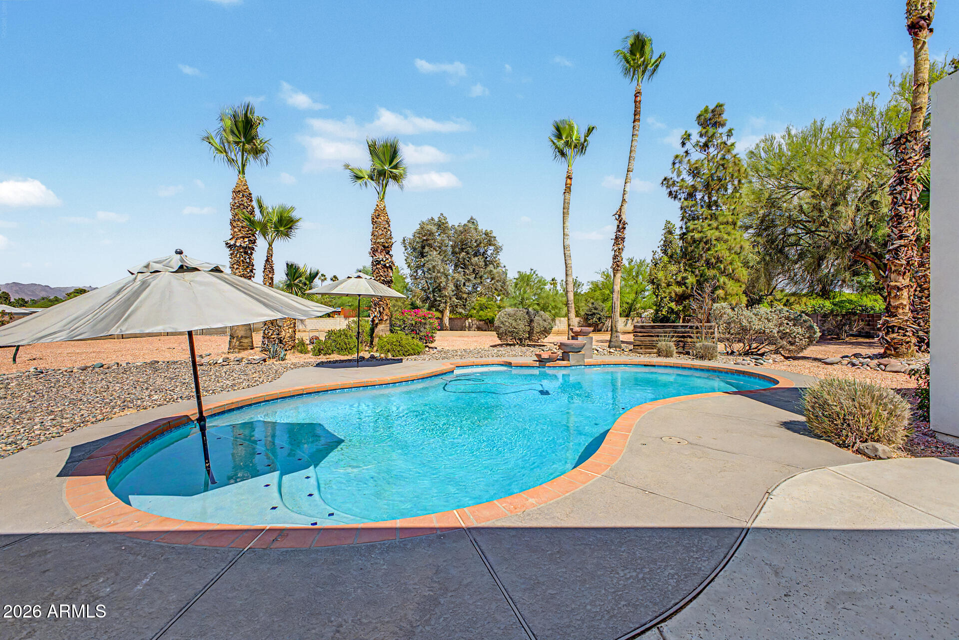 Experience elevated desert living in this exceptional Scottsdale estate, perfectly positioned on an expansive private lot with a circular driveway and impeccable curb appeal. Designed with luxury in mind, this stunning residence showcases high-end finishes throughout, ceilings accented with gorgeous rich wood beams, an immense amount of natural lighting coming through the large front and back windows, and a thoughtfully designed split floorplan offering ultimate privacy. Retreat to the lavish primary suite with a spa-inspired bath designed for relaxation and sophistication. Large, tiled shower with separate soaking tub, his and her sinks, and a primary walk-in closet that would be the envy of anyone who sees it. Both the primary bedroom and closet offer separate entrances to your backyard, and laundry is conveniently located both by the primary and secondary bedrooms. Two secondary bedrooms include their own en-suite bathroom with glass enclosed showers, providing comfort and convenience for family and guests alike, and all bedrooms have walk-in closets. The chef's kitchen features stunning custom white cabinetry and granite counters accented by a large island with black granite counter and cabinets, and stainless-steel appliances with built-in ovens. Your pantry is a room of its own with numerous shelves and separate sink for convenience. Added cabinetry with beverage cooler in your dinette area allows for a coffee bar, liquor display cabinet, and more. This seamlessly opens to your elegant living and entertaining spaces with fireplace. Enjoy movie nights in the theatre room, which also can be used as a dedicated home gym or office. Attached to the main home is an oversized four-car garage with epoxy flooring and in the backyard is a separate two-car garage accessible through the RV gate, which also leads to the expansive RV parking area. Enjoy breathtaking sunsets and views from your backyard complete with a sparkling private pool and ample space to entertain, relax, and take in the Arizona lifestyle.