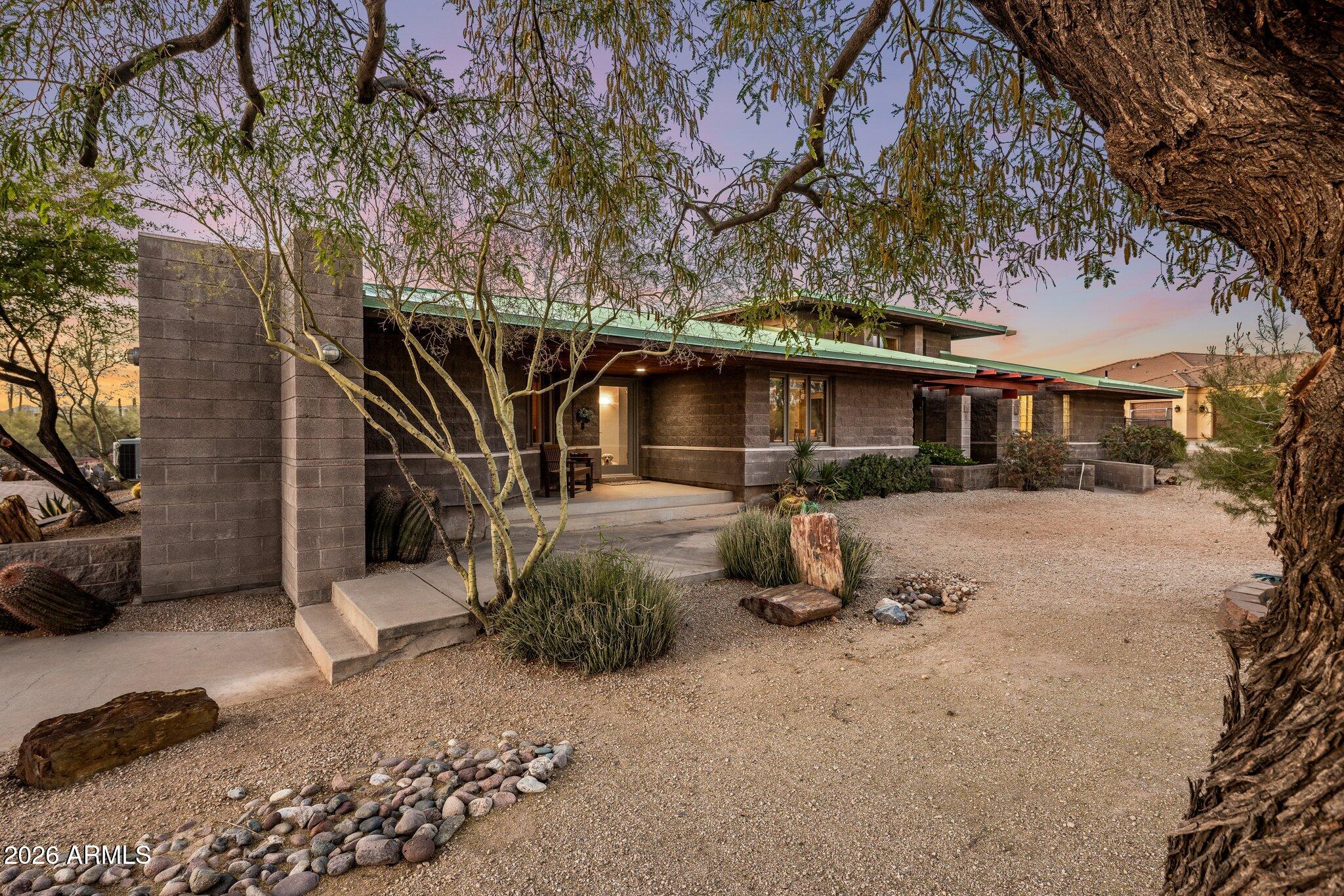 Inspired by the timeless philosophy of Frank Lloyd Wright, this award-winning Green & Green designed residence offers a rare opportunity to own an architecturally significant desert retreat where sustainable design, modern updates and effortless indoor-outdoor living exist in perfect harmony.  Nestled on a north/south facing one-acre homesite in coveted NO HOA Maricopa County Island with horse privileges, the property is thoughtfully positioned to embrace the beauty of the surrounding Sonoran Desert while remaining just minutes from the shopping, dining and entertainment of North Scottsdale and Cave Creek.  Recognized with a Builder's Choice Award, the home showcases passive solar design, exposed block construction, commercial-grade standing seam metal roofing, and R26/R30  insulation - creating an environmentally conscious residence built for lasting beauty, efficiency and comfort.  Recent updates, including a beautifully reimagined kitchen and bathrooms, complement the homes original architectural vision while introducing sophisticated contemporary finishes.  Rich hickory and maple hardwood flooring, soaring ceilings, and walls of glass create warm, light-filled interiors that frame breathtaking views of Black Mountain and the surrounding desert landscape.  The dramatic great room is anchored by a floor-to-ceiling fireplace, while a sculptural circular staircase ascends to a loft overlooking the living spaces, complete with an indoor putting green and endless flexibility as a private office, library, fitness space, or creative retreat.  Guest rooms are versatile with spacious bedrooms, a beautifully appointed three-quarter bath with steam shower, and offer exceptional privacy for guests or multigenerational living, dedicated office, or an inspiring artist's workspace.  Designed to embrace Arizona's extraordinary climate, the outdoor living experience is equally compelling. Expansive patios, a sparkling pool and spa, built-in barbecue, and generous shaded gathering spaces create an effortless connection between architecture and nature - ideal for intimate evenings or memorable entertaining beneath the backdrop of iconic Black Mountain. Distinctive in both design and setting, this is a home that celebrates architecture, sustainability, and the timeless beauty of the Sonoran Desert.  Buyer to verify all material facts. All material information must be verified during the inspection period.