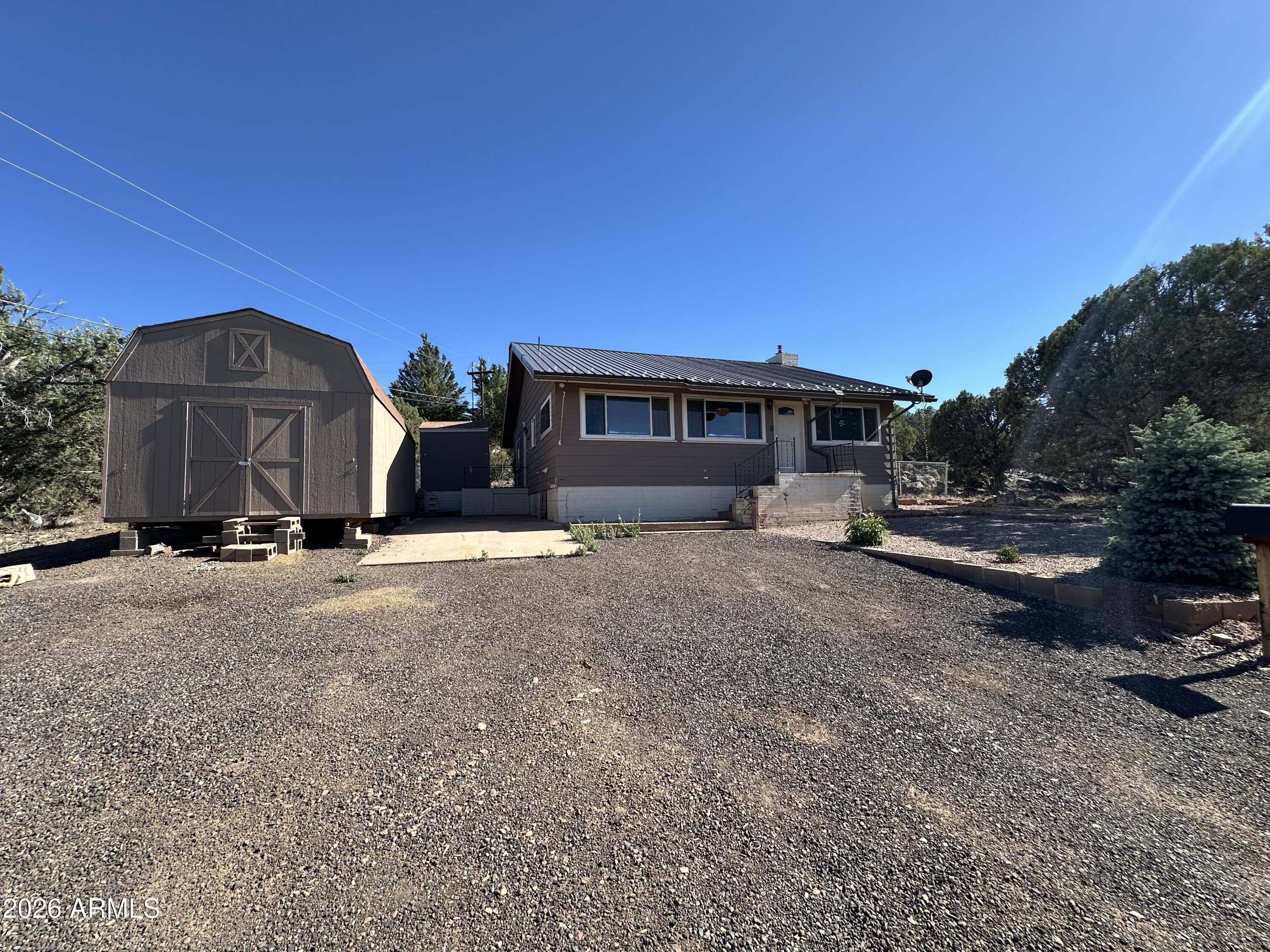 Outstanding value in White Mountain Lakes! This 2-bedroom, 2-bath home also features a bonus room that can easily serve as a 3rd bedroom. Offering 1,292 sq ft on a spacious 0.30-acre lot, this site-built home features an open-concept floor plan, cozy wood-burning fireplace, functional kitchen with breakfast bar, metal roof, and double-pane windows throughout. Enjoy the flexibility of a large storage shed and plenty of outdoor space to relax or entertain. Priced well below competing site-built homes, this is an incredible opportunity for buyers looking to add their own personal touches while building equity. Whether you're searching for a full-time residence, mountain getaway, or investment property, this home offers exceptional value in the beautiful White Mountains.