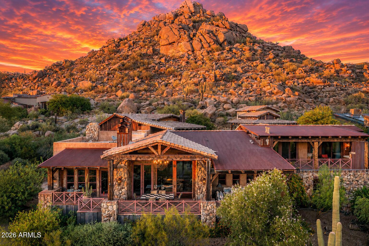 RARE ARCHITECTURE, PINNACLE PEAK VIEWS, DETACHED GUEST HOUSE, & UNMATCHED PRIVACY!

Positioned on an elevated mountainside within Estancia, this architecturally distinct residence captures unobstructed Pinnacle Peak views while delivering a level of craftsmanship that is nearly impossible to replicate.

Designed with an elegant-rustic lodge aesthetic, the home was constructed using a curated palette of imported and reclaimed materials including 150-year-old barn beams, 100-year-old pine flooring, reclaimed wood siding, rusted corrugated metal, and hand-laid stone masonry. Every element was intentionally selected to create depth, character, and a true sense of permanence. The split floor plan offers dual primary suites, an additional guest suite with private entrance, dedicated office, and an enclosed den/media room. A detached guest house provides its own living area, ensuite bedroom, and loft, positioned along a private walking path with elevated community and mountain views.

At the center of the home, a fully enclosed courtyard becomes the focal point - featuring cascading waterfalls, stacked boulders, a bridge over a pebble-lined pool and grotto, Sedona flagstone, and expansive rock fire features. The result is a controlled, immersive indoor-outdoor environment designed for both privacy and experience.

Direct access to nearby hiking trails enhances everyday livability, while recent updates including 2020 HVAC systems, newer roof, and updated appliances provide modern reliability. Four garage spaces complete the offering.

This is not a home you recreate. It's one you acquire.