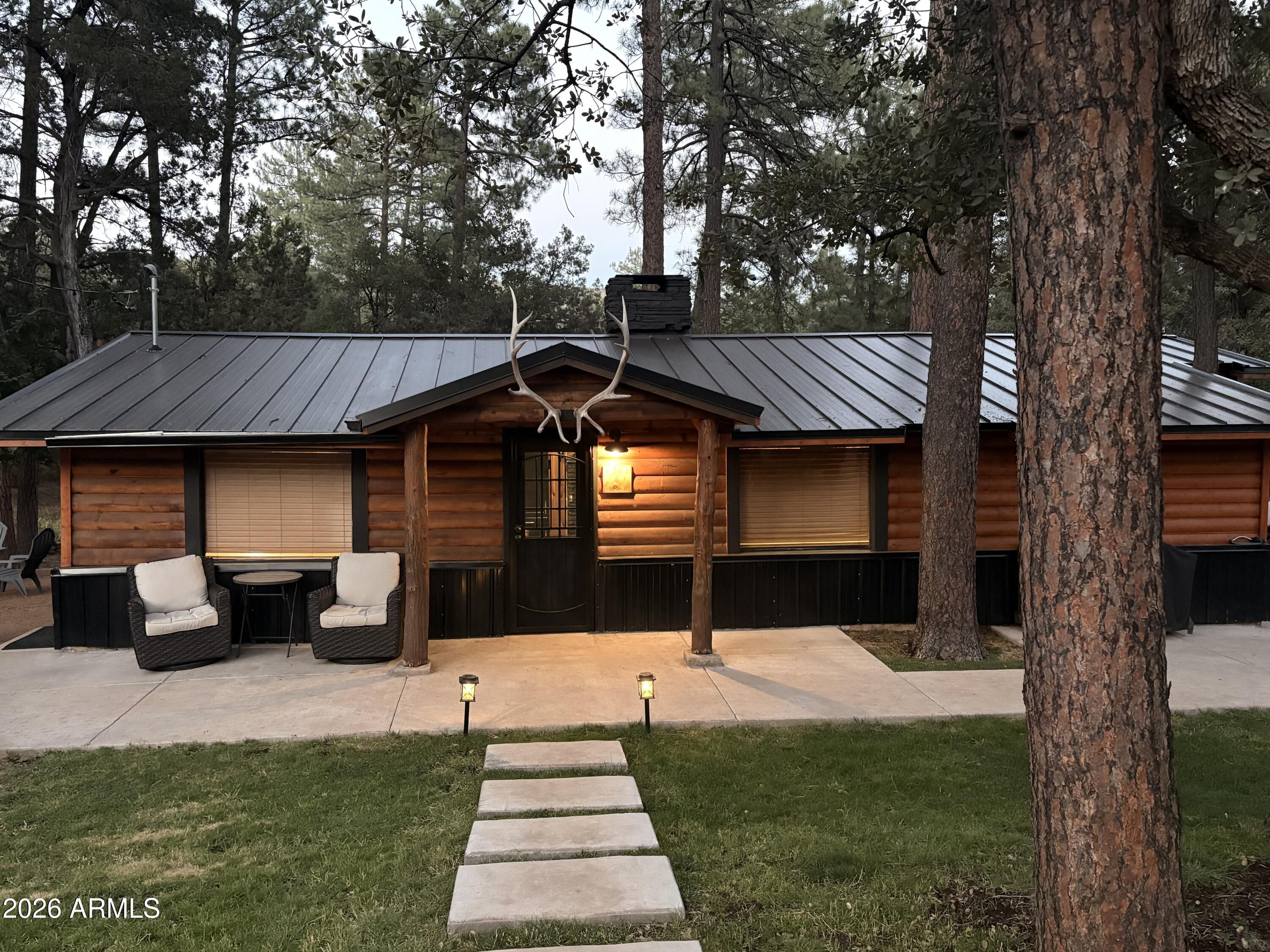 Step into a breath of fresh air at this cozy cabin in Pine, Arizona. Capped with a beautiful metal roof, lined with beautiful black and real wood accents throughout. Located on a dead-end dirt road, this 3-bed, 2-bath home invites you to relax among the towering trees and lush green grass. Spend your afternoons enjoying hikes, mountain biking, hunting, or ATV rides through the cool ponderosa pines of Northern Arizona, or kick back on the porch with a cocktail, watching the elk walk by. Soaking in the views through the large picture windows as the sun sets, cozy up by the wood-burning fireplace on chilly winter evenings or head outside to roast marshmallows around the fire pit. Located In close proximity to shopping, entertainment, restaurants, and coffee shops, this cozy cabin would make a