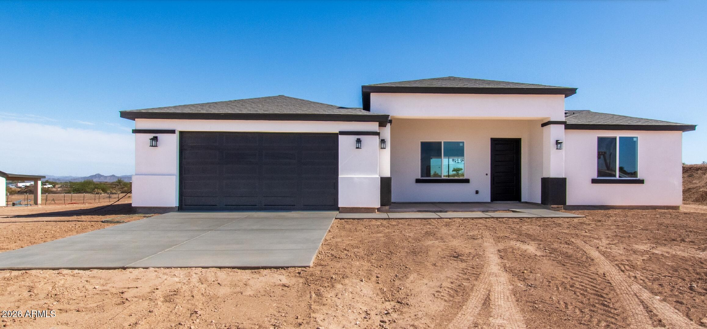 This brand-new construction home in the growing desert community of Tonopah, Arizona, offers the perfect blend of modern luxury and wide-open rural freedom. Designed with an intentional, open-concept layout, this 3-bedroom, 2.5-bathroom single-level property sits on an expansive lot of over 1 acre. It provides sweeping views of the Arizona sky and surrounding mountain ranges.
Great Room: Vaulted ceilings windows create a bright, airy space perfect for entertaining. Modern Kitchen: Outfitted with premium quartz countertops, modern shaker cabinetry, and a large breakfast bar island. Primary Suite: Features a large walk-in closet and a suite full bathroom. Guest Wing: Two additional spacious bedrooms sharing a full secondary bathroom. Powder Room: A convenient half-bath for guest