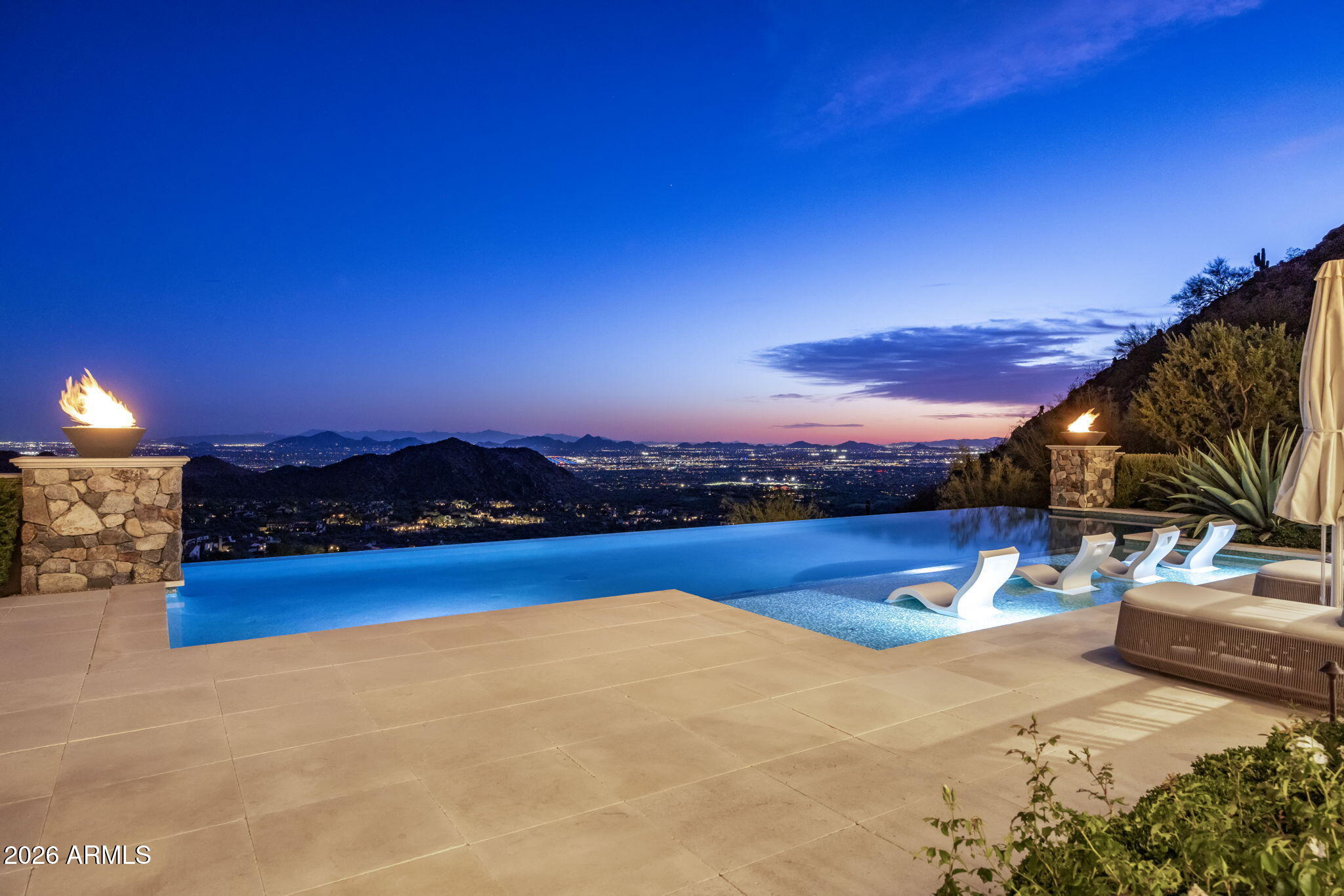 SILVERLEAF GOLF MEMBERSHIP OPPORTUNITY AVAILABLE! Tucked into the coveted ''saddle'' of Silverleaf's Upper Canyon Summit, this 4.67-acre estate by Salcito Custom Homes rests naturally between two mountain hills, creating a rare sense of privacy, drama, and connection to the desert landscape. From its elevated setting, the home captures sweeping views across the Silverleaf Golf Course, surrounding mountains, city lights, and the valley below.
Designed by Dale Gardon, with interiors curated in collaboration with Rebecca Salcito of Salcito Design Group, the residence pairs architectural strength with a warm French Modern aesthetic. European oak flooring, hand-blown glass chandeliers, ombré alpaca draperies, marble fireplaces, and refined custom details create a feeling that is sophisticated, layered, and quietly luxurious.  A private gated drive leads to an impressive motor court with air cooled and heated garages with a capacity for up to 11 vehicles, ideal for the car collector or enthusiast. Inside, the main level opens to expansive living spaces thoughtfully designed to frame the views at every turn. The great room, dining area, and outdoor terraces flow effortlessly together, creating a home equally suited for intimate everyday living or large-scale entertaining. The kitchen is both striking and highly functional, featuring Bulthaup cabinetry, integrated appliances, a breakfast cabinet, and Calacatta marble waterfall countertops with a leathered finish. A separate catering kitchen adds another level of convenience for hosting, while the dining area is anchored by a dramatic wine wall. The owner's retreat is positioned as a private sanctuary, complete with a marble fireplace, sitting area, and direct access to a secluded spa cove. The spa-inspired bath features marble floors, showers, and vanities, Baccarat crystal knobs, custom wood cabinetry with integrated hardware, a matte white soaking tub, and a dramatic 14-foot Bubble chandelier. Additional living spaces include a main-level offices, an upstairs en-suite room that can function as a private office, guest suite or a craft room and a lower-level entertainment area with a spacious family room, game room, soundproof music room, wet bar, two additional en-suite guest rooms and two laundry rooms. A detached guest house offers its own living room, bedroom, garage, and exceptional views, creating a comfortable retreat for visitors. Outdoor living is one of the estate's defining features. Multiple covered patios, fire features, lounge and dining areas, a double-sided pop-up television cabinet, infinity-edge pool, and private spa create a resort-like environment that feels fully integrated into the surrounding mountainside.
Located within Silverleaf, one of North Scottsdale's most prestigious guard-gated communities, this Upper Canyon Summit residence offers a rare combination of scale, craftsmanship, privacy, views, and architectural presence and featured in the publications "Iconic," "luxe Interior + Design," "Modern Luxury Interiors." This hillside estate designed not only to impress, but to live beautifully.