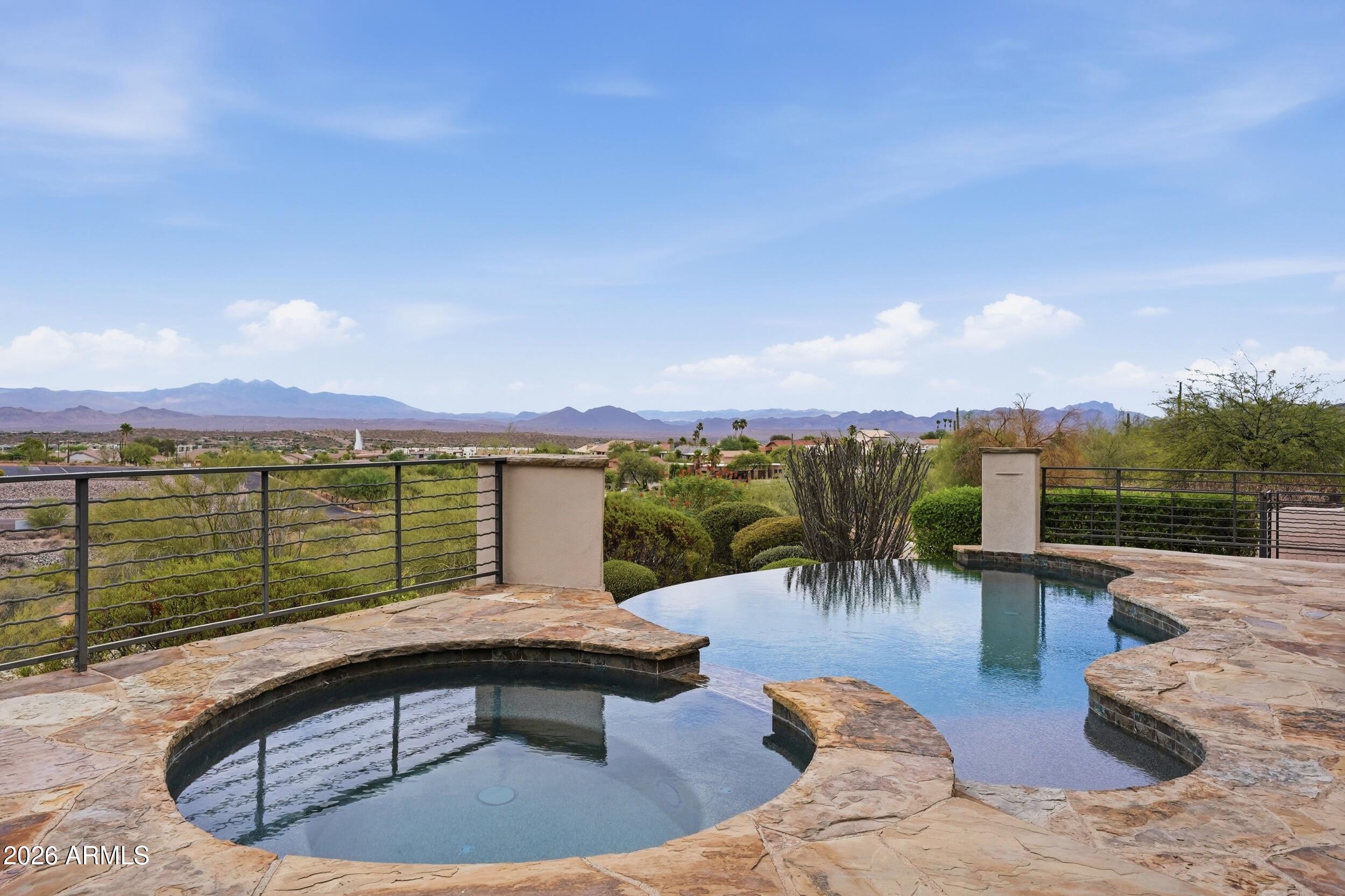 You dreamed it--now make it your reality. Experience unparalleled privacy, breathtaking panoramic views, and exceptional custom craftsmanship in this extraordinary hillside estate. Nestled on more than 3 acres of pristine Sonoran Desert, this remarkable residence offers the perfect balance of luxury, comfort, quality, and functionality. A long driveway creates an exclusive access, setting the home well apart from the street and neighboring properties for a true sense of privacy.  Enter through the tranquil gated courtyard and discover thoughtfully designed living spaces where expansive windows frame spectacular mountain, desert, and city views from nearly every room. The inviting great room, anchored by a beautiful fireplace, flows seamlessly into the gourmet kitchen and dining area, creating an ideal setting for everyday living and effortless entertaining. The chef's kitchen features premium appliances, abundant custom cabinetry, generous counter space, and an oversized island designed for gathering with family and friends.
The luxurious primary suite is a private retreat, thoughtfully separated from the secondary bedrooms and complete with its own fireplace, spa-inspired bath, oversized walk-in closet, and direct access to the upper view patio. Two additional bedrooms each offer en-suite bathrooms and walk-in closets, providing exceptional comfort and privacy for family or guests.
A fully equipped attached guest apartment offers incredible flexibility with its own HVAC system, kitchenette, living room, bedroom, and private bath--ideal for multigenerational living, extended guests, or a private home office. A dedicated office near the entry, a versatile flex room perfect for a gym or hobby space, and an additional lower-level suite with a full bath and direct access to the backyard provide endless possibilities to fit your lifestyle.
Step outside to a backyard unlike any other. The resort-style outdoor living space showcases a negative-edge pool, spillover spa, fire pit, built-in BBQ, and multiple entertaining areas--all perfectly positioned to capture unobstructed views of Four Peaks, surrounding mountain ranges, The Fountain, sparkling city lights, and unforgettable Arizona sunsets. The seamless indoor-outdoor design creates an extraordinary setting for relaxing, entertaining, and appreciating the beauty of the desert landscape.
With no HOA, exceptional construction, unmatched privacy, and some of the most captivating views Arizona has to offer, this one-of-a-kind estate delivers a luxury lifestyle that is truly beyond compare. This is more than a home--it is an experience that must be seen in person to be fully appreciated.