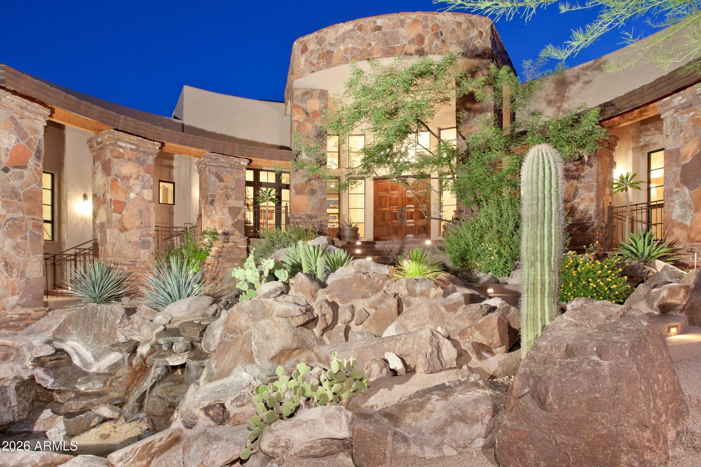 Tucked into a mountain on a cul-de-sac road in prestigious, privately gated Canyon Reserve, this distinctive, custom-built residence beckons even from a distance. With a multi-tiered roofline that echoes the mountainous landscape surrounding it, the natural stone exterior serves to accentuate that effect. As the red and gold hues of the natural stone contrast with the dark tones of the landscape, this home glistens by day
and sparkles by night. From the very first glimpse of this grand residence, you realize this one-of-a-kind home offers a heightened level of living.

The front walkway delights the senses, as the meditative sounds of the cascading
waterfall serenade you while walking across a bridge to access the concave entrance. The 10-foot cherry hardwood front doors open to a grand foyer with soaring ceilings. At this moment it becomes evident that this refined home is an architectural showcase drenched in luxurious bespoke details from its structure and tasteful use of textures
and tones. A blend of Hickory hardwood flooring, stone tiles, and large windows with wood trim provides the foundation for these exceptional finishes. Abundant natural light weaves through the home creating a true indoor/outdoor atmosphere. As the sheer
beauty of this home begins reveals itself, you will exhale and realize that you have finally arrived.

Encompassing just over 7000 sq ft, with four bedrooms, seven baths, a Den/Office, Media/Room, an oversize 3-car garage with additional flex space, and resting on 6.89 acres, this gracious home has generous accommodations for entertaining family and friends.
The warm and inviting atmosphere welcomes you in, and a meticulously executed floor plan anticipates seamless ease of movement from room to room. Graciously greet your guests in the spacious Living room with 15-foot ceilings, appointed with a
large Canterra stone gas fireplace with herringbone brick pattern. The floor to ceiling windows reveal the backyard retreat, creating the perfect backdrop to entertain your guests. The adjacent Wet Bar, with cabinets, fridge and ice maker, allows for effortless
entertaining, and the adjoining Dining Room, with beautiful gas fireplace and pocket doors for privacy, offers an elegant and comfortable setting.

The bright and airy Breakfast room may be accessed from the foyer and leads to an impressive Chef's Kitchen. This highly elegant dream kitchen is rich with design details including beautifully tiled floors and backsplashes. With high-end appointments that would delight any chef, it features bull-nose edge granite countertops, custom-built cabinetry, Viking gas range with two ovens and pot-filler, built-in Viking microwave,
Sub Zero refrigerator, large farmhouse sink with pull-out faucet, and dedicated instant hot water faucet. The expansive island offers additional cabinets for storage and features a granite countertop, vegetable sink, vacuum switch disposal, ice maker, and
trash compactor. There is also a dedicated walk-in pantry room with floor to ceiling storage, and a Butler's pantry. A custom designed beehive fireplace adds ambiance to the space while the large granite Breakfast bar extends into the spacious Family
Room where the soaring 15-foot-high ceilings add drama, and floor-to-ceiling windows fill the space with natural light.

The spacious and relaxing Primary suite with ensuite bath will become your personal sanctuary. This serene retreat includes a cozy fireplace, sitting room, refrigerator, and unparalleled panoramic views from 8 foot high windows. Open the glass door to unwind on the patio before bed or to witness a glorious morning sunrise. The over-size walk-in closet takes on the functionality of a dressing room and features handsome custom-built cabinetry with plenty of drawers and a shoe closet. It is certain to please
any fashionista! The soothing spa-like ensuite bathroom features bull-nose edge granite countertops, a spacious vanity with dual sinks , jetted spa, double- headed snail shower, and private powder room. This restful suite becomes the perfect retreat at the end of a long day.
Three comfortable size secondary bedrooms with ensuite baths are situated on the same wing of the home and feature dazzling mountain views, and walk-in closets. A separate covered patio is accessible from two from the bedrooms. Also located on this same wing is a sizable media room which could also become a child's play room. Three elegant half baths are perfect for your guests, one of which is a pool bath accessed from the backyard. 

An impressive, resort-style backyard is impeccably designed for entertaining and leisurely afternoons, offering 3,000 sq ft of outdoor space with four covered patios. Head through the door in the Family room to a cozy covered patio with two spaces,
one with a large two-sided gas fireplace. You will enjoy the warmth of the fireplace from the heated Jacuzzi spa with waterfall on the opposite side. A stunning natural stone wall emphasizes the curved shape of the large sparkling pool where you can relax and meditate to the sound of the dramatic waterfall cascading into the pool. A
second covered patio with dramatic handcrafted stone supports offers an elegant, yet casual space for dining and lounging. An outdoor kitchen with granite countertop, Viking gas grill, sink, refrigerator, and the convenience of a pool bath makes for effortless entertaining and casual pool-side dining. You will love hosting your family and friends with all these outdoor amenities.

Car lovers will appreciate the extended length and over-size height of the 3-car garage with ample storage. The bonus space off the garage offers lots of potential to adapt to your lifestyle. Behind an electric roll-down door you will find a large room that could be used as a gym and an additional room may make the perfect hobby room.

This distinctive residence in the prestigious, privately gated community of Canyon Reserve, with dramatic, sweeping mountain views, offers the privacy and sanctuary you seek. A true architectural gem, it exudes all the luxurious, bespoke details you
would expect in a custom built home where timeless elegance blends with a warm and inviting atmosphere. This meticulously custom home offers the refinement, refuge and elevated lifestyle that you have been looking for.

It's time to exhale... You have arrived.