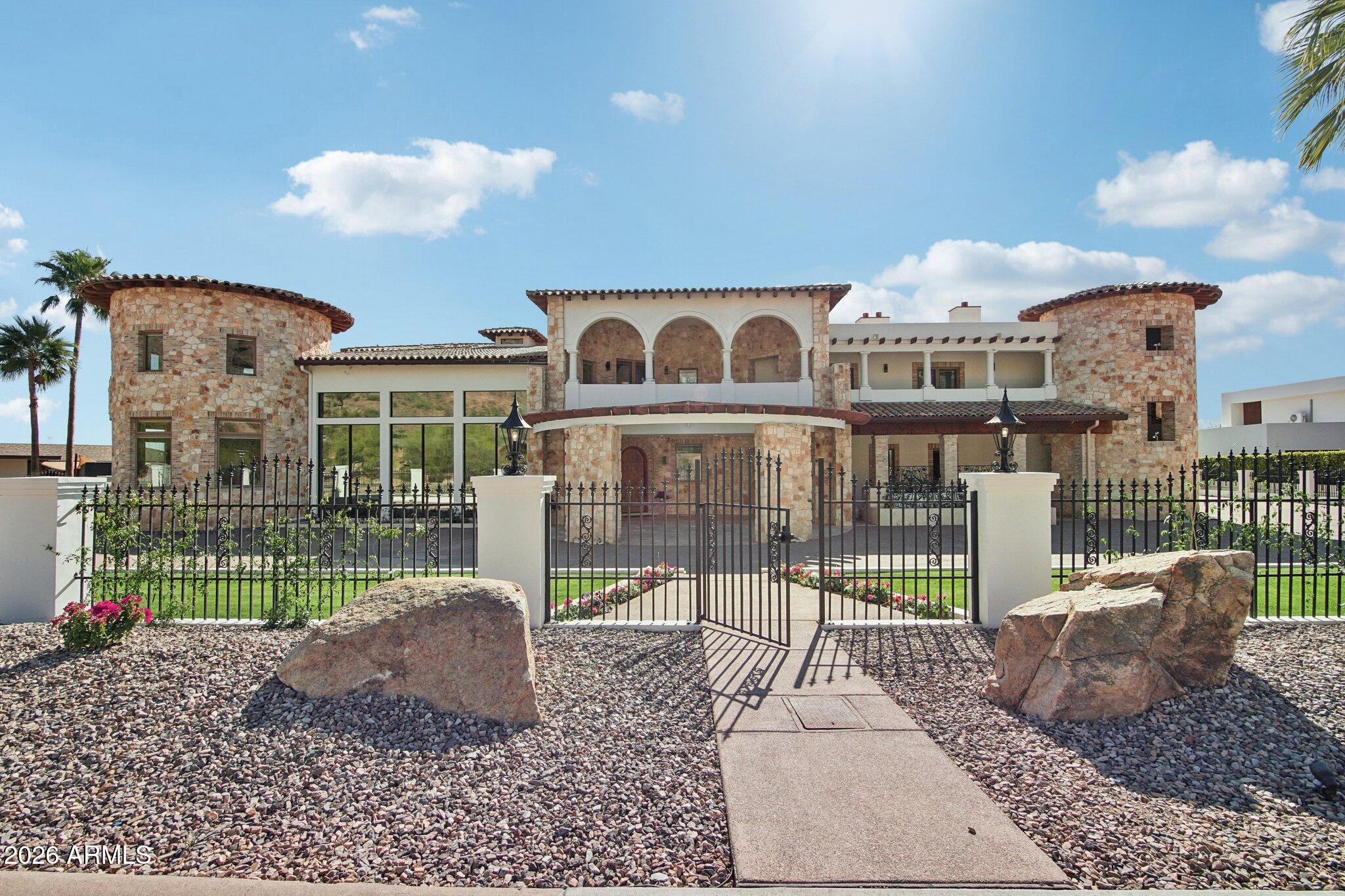 Privately gated on over 1.09 acres in prestigious Arcadia Proper -one of Phoenix's most sought after neighborhoods. The Rockridge Estate captures panoramic views of the city skyline and Camelback Mountain as its backdrop. A grand porte-cochère arrival leads to soaring, architecturally rich interiors, where a dramatic 15' wall of glass frames the view. The resort-style backyard is anchored by a two-level infinity-edge pool with a 10' water wall, grotto, and water slide. Spanning over 13,000 sqft, the estate offers 7 bedrooms, including two primary suites, 9 bathrooms, 5 fireplaces, an elevator, and expansive living spaces designed for elevated living and entertaining. The chef's kitchen serves as the heart of the home, appointed with Wolf and Sub-Zero appliances , dual cooking surfaces, and a curved run of custom cabinetry and quartzite countertops beneath a wall of windows. An expansive multi-level island, farmhouse sinks, and walk-in pantry are complemented by a secondary pantry, laundry, mudroom features, and dedicated dog spa.
The upper level, accessed from the beautiful wrought-iron railed grand staircase, or private elevator, offers a loft overlooking the main living areas and a north-facing veranda capturing Camelback views. A game room with wet bar, fireplace, en-suite bedrooms, and optional private access creates a flexible secondary living environment.
The upper-level primary suite spans approximately 2,000 sqft with fireplace, terrace, and sweeping views, complemented by a spa-inspired bath, boutique-style closet with laundry, and adjoining flex space. A rotunda office or studio and lower-level vault with wine cellar or simulator potential add further versatility.
Lush, park-like grounds unfold across multiple levels with illuminated staircases and expansive terraces. A striking two-level infinity-edge pool cascades over a 10-foot water wall, with a lower-level grotto, water slide, and lounge areas, and an upper level featuring an infinity-edge spa spilling into both tiers, in-water seating, and sun shelf. A covered patio with BBQ and bar seating for 12, motorized shades, and custom awning supports year-round enjoyment. An elevated deck and rooftop lounge capture panoramic city, mountain, and 360-degree views -creating a seamless indoor-outdoor experience at every level.
An attached two-car garage is complimented by a detached RV garage with additional bays, accommodating 10+ vehicles, recreational storage, or car collections. A dedicated RV gate and expanded parking areas maintain the integrity and flow of the grand circular drive.
Set at the base of Camelback Mountain in Arcadia Proper, with close proximity to premier dining, shopping, and lifestyle amenities.