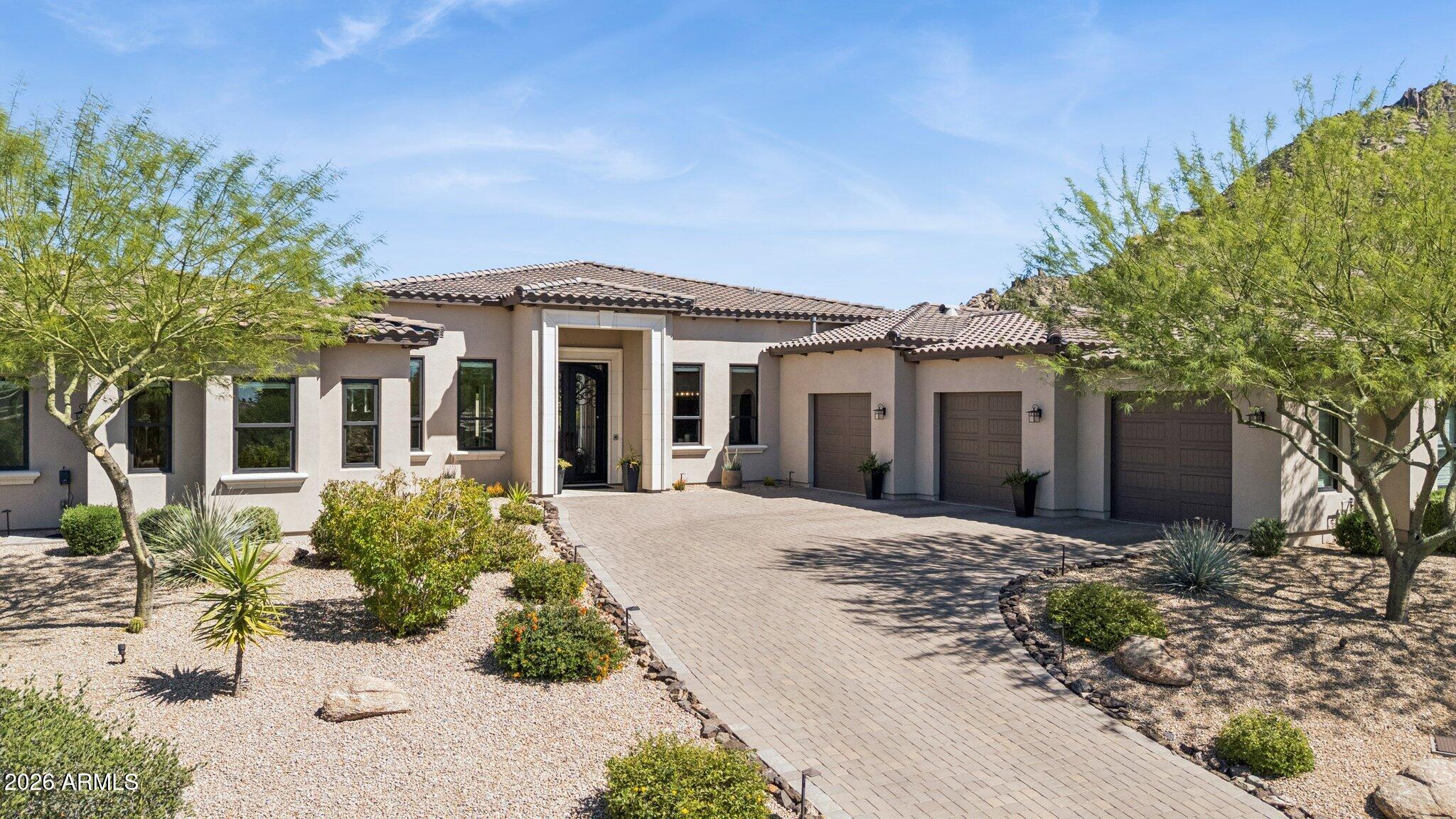 Framed by dramatic Troon Mountain and Pinnacle Peak views, this exceptional single-level contemporary luxury estate in guard-gated Windy Walk Estates delivers the ultimate North Scottsdale lifestyle. Situated on an expansive private cul-de-sac lot, the home offers resort-inspired living, premium modern luxury finishes, smart home technology, dramatic architecture with no interior steps, and breathtaking mountain and sunset views. This custom home built in 2020, with 4 bed, 3.5 bath, 2 offices plus bonus room, showcases a stunning open-concept great room with soaring ceilings, dramatic fireplace, and expansive glass doors that frame the surrounding mountain landscape and spectacular Arizona sunsets. Throughout the main living areas, tumbled travertine flooring in an elegant Versailles pattern adds warmth, character, and timeless desert style.

The gourmet chef's kitchen is designed for both entertaining and everyday living, featuring custom cabinetry, leather-textured granite countertops, an oversized island, walk-in pantry, with and professional-grade Thermador appliances including double wall ovens, 48" gas range and convenient plumbed built-in coffee bar. A breakfast room and bar seating complement the formal dining area highlighted by a striking climate-controlled wine room with iron and glass door and 700+ bottle capacity. A well-appointed butlers pantry/prep area with wet bar and wine fridge further enhance the home's entertaining capabilities. 

The private primary retreat offers a luxurious sanctuary with sitting area, spa-inspired bath, freestanding soaking tub, dual vanities, expansive custom walk-in closets, and a spectacular oversized walk-through shower with dual entry and floor-to-ceiling designer tile. The primary suite also enjoys its own private patio with fire pit and stunning Pinnacle Peak views - an inviting space for quiet mornings or sunset evenings. 

Guest accommodations are equally impressive. One wing of the home features a separate attached guest suite designed as a private retreat, complete with its own living room, mini refrigerator, sink, private entrance, luxury upgraded en-suite bath, and walk-in closet. Large windows frame beautiful views of Pinnacle Peak, creating an ideal space for extended stays, multigenerational living, or a private retreat. Two additional guest bedrooms feature a Jack-and-Jill luxury en-suite bath and share a flexible bonus lounge area ideal for a media space or secondary living room. Both bedrooms enjoy direct access to the pool and patio, enhancing the home's seamless indoor-outdoor lifestyle. 

The home also includes two private offices or dens, perfect for today's work-from-home lifestyle. One office features custom built-in cabinetry and space designed for a safe, providing both functionality and security.

Step outside to a resort-style backyard designed for unforgettable entertaining. A shimmering Pebble Sheen saltwater pool with Baja shelf, swim-up bar seating, cascading water features, and dramatic fire elements creates a stunning focal point against the mountain backdrop. Expansive covered patios provide inviting outdoor living spaces overlooking the pool and Troon Mountain beyond. A show stopping sunken ramada outdoor kitchen features built-in BBQ, professionally constructed pizza oven, TV and bar seating--perfect for entertaining under the Arizona sky. Travertine patios, lush desert landscaping, citrus trees, and custom lighting complete the private desert oasis.

Elevating the experience even further is a rooftop view deck offering panoramic views of Troon Mountain, Pinnacle Peak, and distant city lights, plumbed for a gas fire pit--an ideal setting for sunset gatherings or stargazing.  

This extraordinary home is further enhanced by Savant smart home automation controlling lighting, climate, pool, fireplace, appliances, HVAC, entry camera, and more, along with whole-house audio and integrated CAT6 and Araknis wireless mesh network wiring. Remote-control motorized shades, water softener, reverse osmosis system, over 16 TV locations and multiple HVAC zones add convenience and comfort throughout the home. The residence is also built for performance and energy efficiency with spray foam insulation for exceptional quiet and thermal efficiency. 

The insulated 4 car garage with oversized bays offers epoxy floors, extensive custom cabinetry, insulated doors and walls, added storage area and 60amp Level 2 EV charging capability. A well-designed laundry room offers custom cabinetry, generous workspace, sink, refrigerator, and a dedicated dog wash and shower area designed for effortless pet care and everyday convenience.

Located in one of North Scottsdale's most coveted communities, Windy Walk Estates offers privacy and prestige just minutes from Troon Country Club, world-renowned golf, hiking trails, fine dining, and luxury shopping. A rare opportunity to experience elevated desert living with breathtaking views in the heart of Troon Village.