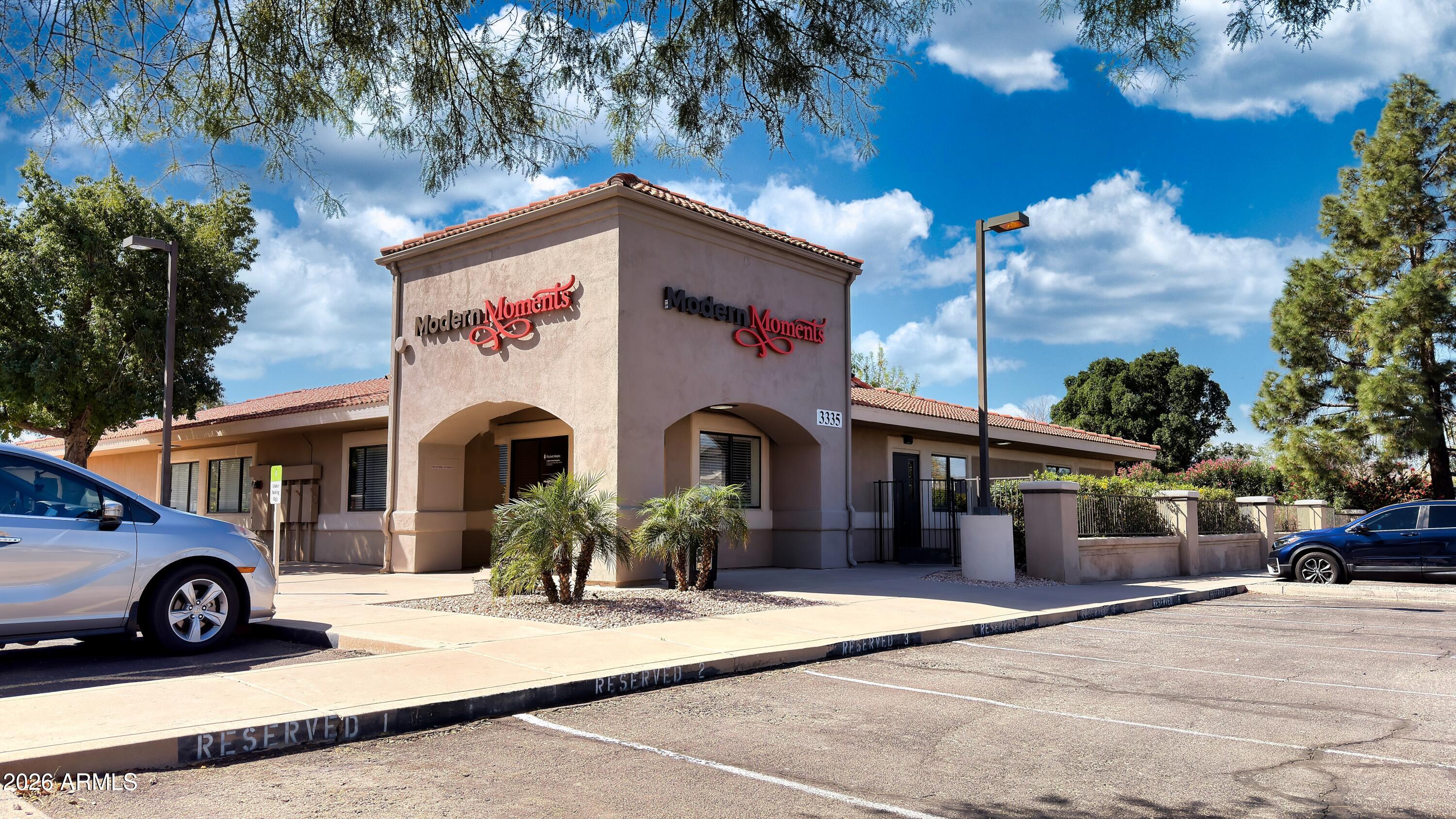 Offered at $2,475,000 -- rare opportunity to own a fully operational, income-producing mixed-use commercial building on a coveted full acre in the heart of Gilbert's Baseline Rd corridor. This 6,702 SF single-story building -- one of very few office properties in the area sitting on over an acre of land -- operates simultaneously as a professional office complex during the week and a thriving wedding and special events venue on weekends through the established Modern Moments. The property features a stunning outdoor event lawn with ceremony arch and overhead string lights, a beautifully appointed indoor ballroom with exposed-beam ceilings, custom draping, crystal chandeliers, and a full hedge wall backdrop, plus a state-of-the-art conference and presentation suite with dual displays, whiteboard, projector, and flexible seating for up to 50. A professional podcast and media production studio rounds out the offering. Two established tenants -- software / media and event professionals -- provide immediate diversified income. With 27,000+ daily vehicles passing the front door and the 2026 assessed market value up 28% year-over-year to $1,676,100, this is a genuinely one-of-a-kind dual-revenue-stream asset in one of Arizona's fastest-growing communities.