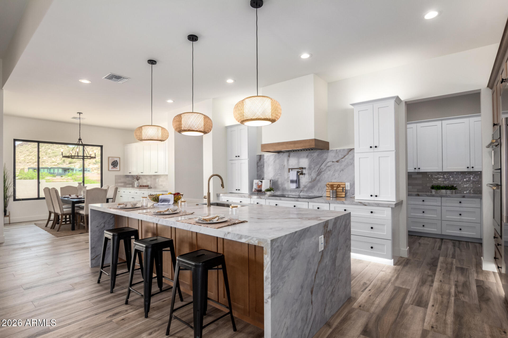 Newly completed Hacienda Arizona Homes estate on over ½ acre in a gated enclave with stunning Superstition Mountain views. Built with 2x6 construction and 12' ceilings, this single-level home offers 4 bedrooms + office, 4 baths, and seamless indoor-outdoor living through expansive glass sliders. Designer kitchen features a waterfall quartz island, custom hood, and walk-in pantry with secondary fridge space. Private-entry guest suite and spa-inspired primary retreat with patio access. Newly finished backyard includes turf, built-in BBQ island, gas fireplace, paver patio, and landscape lighting, perfect for Arizona sunset entertaining. Anderson windows, Trane HVAC, and wood-look porcelain tile throughout.