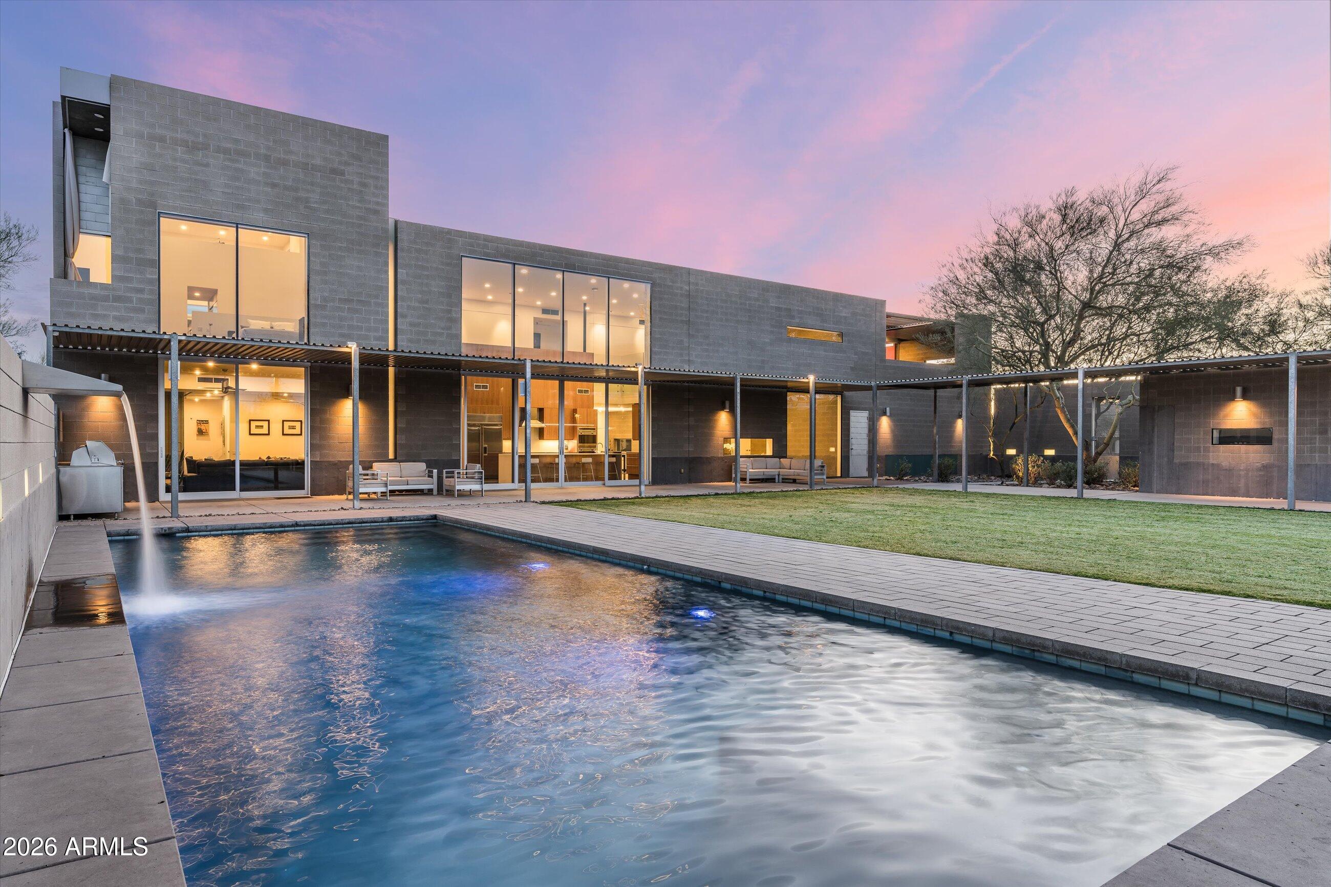 Featured in Dwell and Phoenix Home & Garden plus award winning kitchen design. Essence of the Desert, an architecturally distinct estate designed by architect Amit Upadhye. This home reflects a disciplined approach to form, scale, and modern living.
Set on over an acre with 100' set back and expansive views of the McDowell Mountains, the property balances privacy with a strong connection to its desert surroundings. The timeless architecture emphasizes precision and permanence, with a palette of industrial, high-quality materials-100% poured in place concrete and block construction-selected for both durability and visual impact. Floor-to-ceiling glass frames mountain views and floods the interiors with light, blurring the line between inside and out. Volumes are carefully proportioned to deliver moments of architectural clarity alongside comfortable, livable spaces ideal for both everyday living and sophisticated entertaining.
The main residence offers four bedrooms, four full bathrooms, and two half baths, organized to create a natural flow between private retreats and open living spaces. A dedicated office provides a quiet, design-forward workspace, while a gym or flex room adds versatility. The main home is complete with a  four-car garage, fully integrated into the architecture, maintaining the home's clean, intentional lines.
A fully self-contained guest house enhances the estate, featuring two bedrooms, one bathroom, a full kitchen, laundry, and a private one-car garage- perfect for extended stays, multigenerational living, or hosting with complete independence.
The backyard is designed as a private outdoor retreat, anchored by a large resort-style pool, a ramada with fire feature, and an expansive grassy play area- offering rare versatility for both recreation and relaxation within a modern desert setting.
Every element of the property reflects a commitment to thoughtful design, quality construction, and enduring architectural relevance. This is a published architectural residence that offers scale, privacy, and mountain views for the buyer who values modern design, craftsmanship, and authenticity.