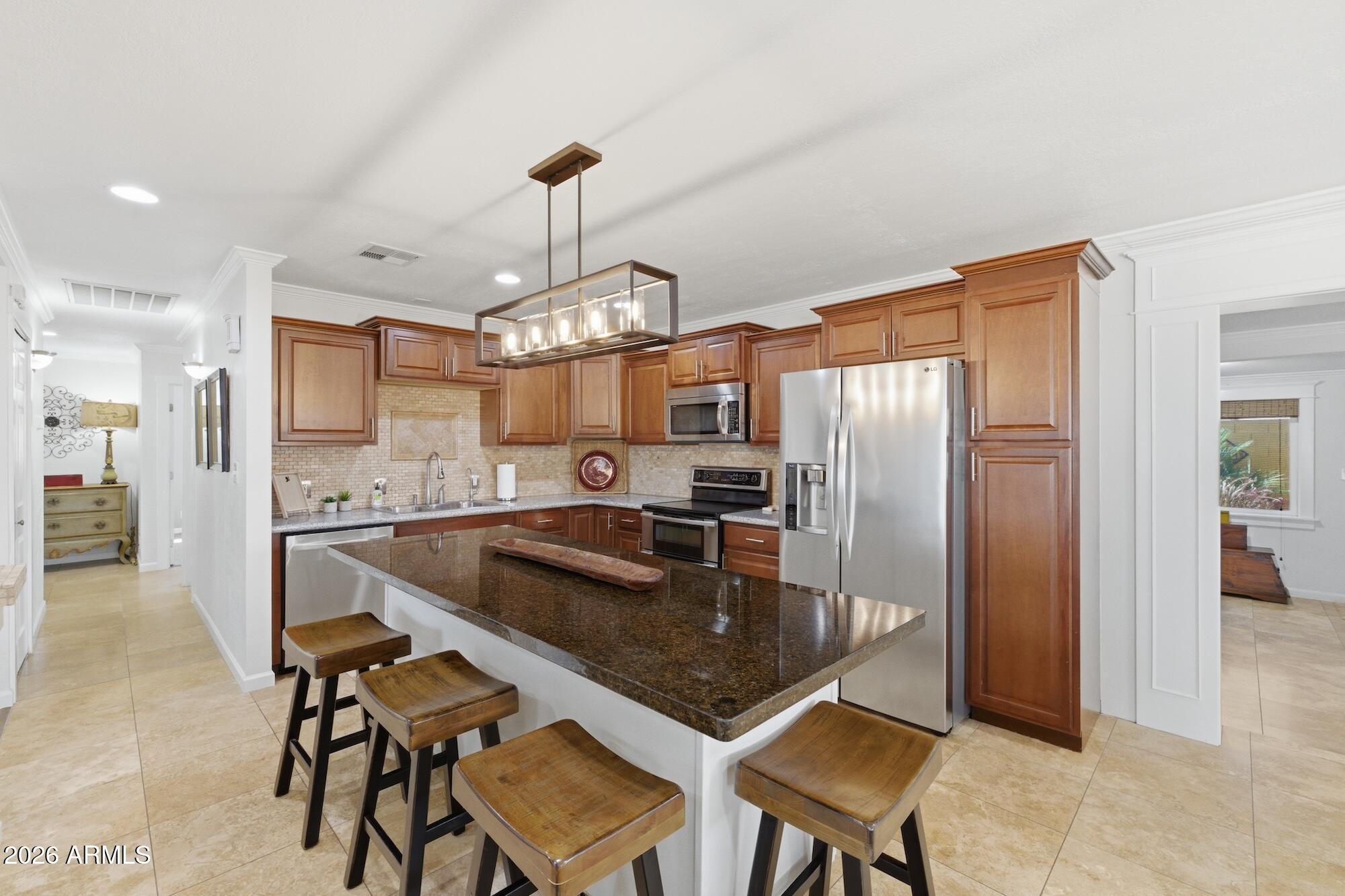 Welcome to this immaculately maintained 4-bedroom, 2-bath home. The beautifully remodeled kitchen is the heart of the home, featuring rich cabinetry, stainless steel appliances, custom backsplash, oversized island with seating, abundant storage, and an open layout that flows seamlessly into the dining and living spaces. Multiple gathering areas include a bright living room, formal dining area, and spacious family room with a cozy fireplace. The primary suite offers a peaceful retreat with its own ensuite bath. Step outside to enjoy the backyard with new turf and space to relax under the pergola. With newer A/C and a prime location near ASU, Downtown Tempe, Scottsdale, the 101, 202, Sky Harbor, parks, and the Phoenix Zoo, this home delivers the perfect blend of comfort, style, and location.