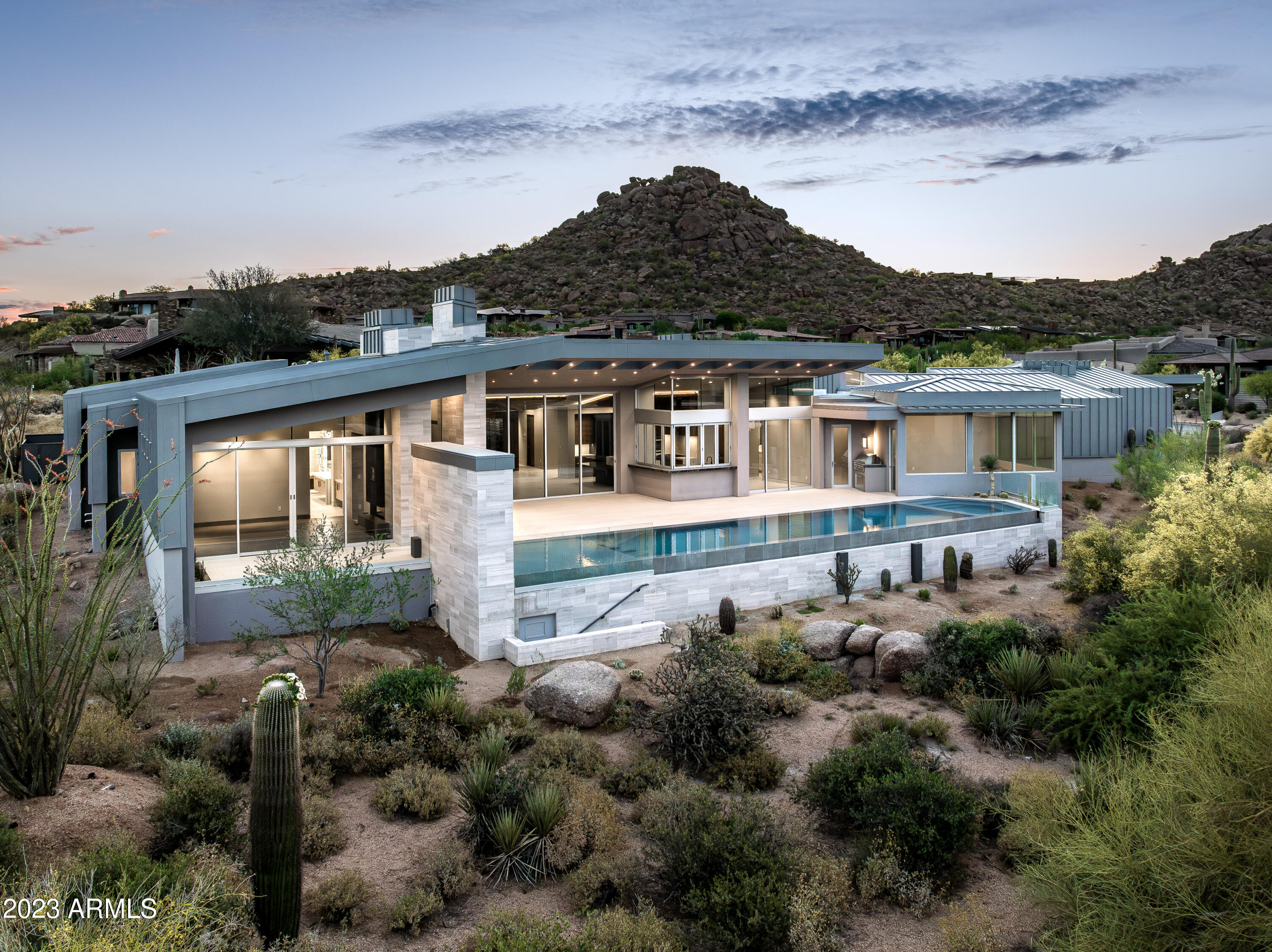 Estancia Golf membership available subject to board approval * Please inquire about Golf Membership availability * The award winning team of GEF Development and Craig Wickersham (Architect) have collaborated to create a timeless, Desert Contemporary-style home in Estancia. Just completed and sited on one of the last golf course lots remaining in the community with southwest-facing solar orientation and panoramic views of Pinnacle Peak. The geometrically diverse architecture is meticulously designed with angled roof lines and trellised eaves to capture each view and provide the optimal amount of natural light. The single level (zero interior steps), modern floor plan is bright and open with a massive great room, floor-to-ceiling windows and pocket doors to the outside living areas. There is a total of 5,500 square feet with a split master suite, 2 guest suites, a guest casita and an office.
The large pool runs in a linear fashion across the length of the outdoor living space that includes a heated spa, large covered patio, outdoor living room with fireplace, BBQ station and indoor/outdoor bar. A 4-car garage completes the residence.