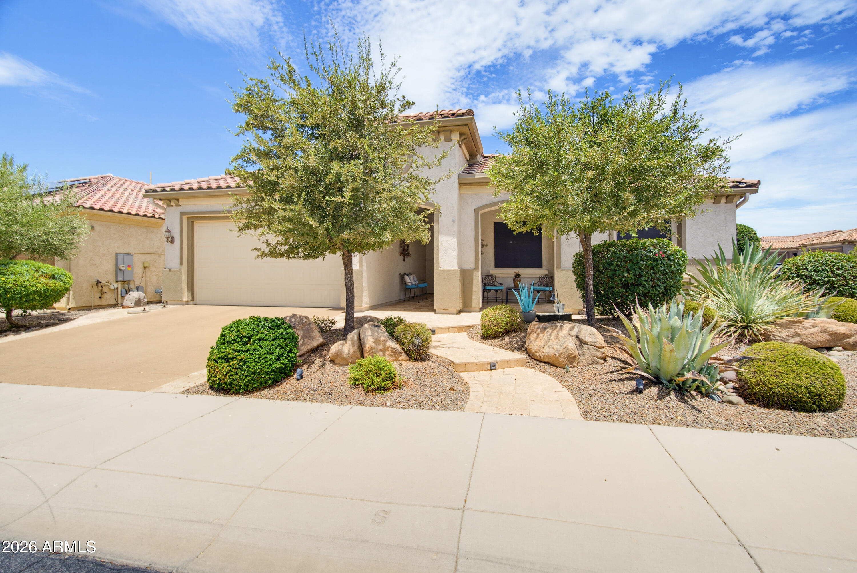 Exceptional Pursuit model featuring 2 bedrooms, 2.5 baths, a versatile office/den, & an outstanding location with scenic mountain views. Attractive curb appeal showcases a travertine walkway & extended front porch. The open-concept floor plan offers a spacious gathering room & dining area with a bay window. The gourmet kitchen features staggered cabinetry, quartz countertops, custom tile backsplash, & an expanded coffee bar. Natural gas ready fireplace. The office/den includes wood flooring & a custom Murphy bed. Plantation shutters, designer paint, & ceiling fans enhance the interior. The spacious primary suite offers dual vanities, a walk-in shower, & a large walk-in closet. Enjoy the extended travertine patio with waterfall, plus an extended garage with epoxy floors & overhead storage.