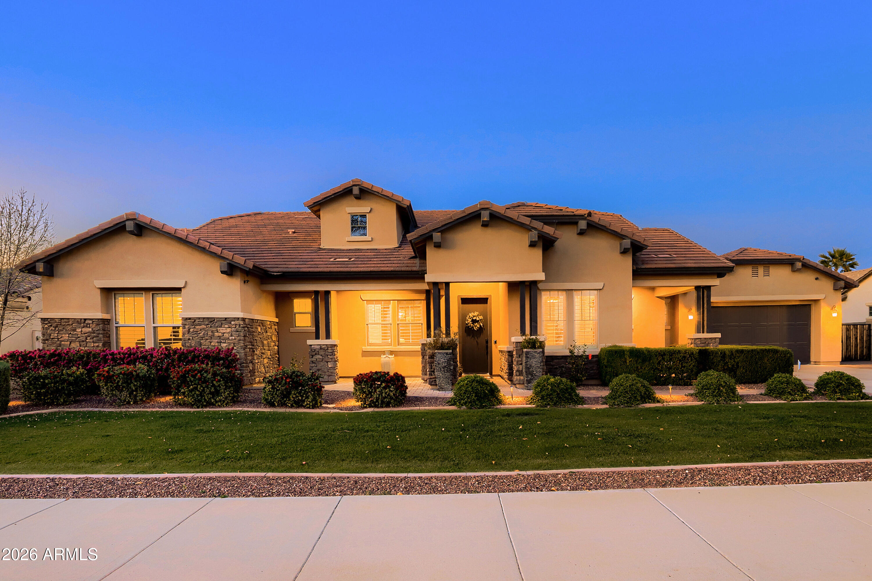 Exquisitely maintained & thoughtfully upgraded, this stunning residence in The Village at Litchfield Park offers refined elegance, exceptional craftsmanship, & effortless Arizona indoor-outdoor living. From the moment you arrive, the home's charming curb appeal & extended cobblestone front patio create a warm & sophisticated welcome. Inside, superior finishes & attention to detail are evident throughout, including custom lighting fixtures, tray ceilings, plantation shutters, designer window treatments, & engineered wood flooring. At the heart of the home is the chef's kitchen, beautifully remodeled in 2024, featuring premium appliances including a 6-burner JennAir gas range, upgraded cabinetry w/ crown molding, & an impressive, oversized island w/ bar seating. A spacious walk-in pantry & convenient butler's pantry provide exceptional storage & preparation space. The adjacent breakfast nook enjoys serene views of the resort-style backyard, your own private tropical retreat. The custom-designed pool is a true showpiece, highlighted by a dramatic waterfall, gas fire bowls, Baja deck, & built-in table w/ wraparound seating, creating an unforgettable setting for relaxation or entertaining. The Great Room perfectly captures Arizona's signature indoor-outdoor lifestyle, w/ a dramatic wall of glass that opens seamlessly to the extended paver patio, complete w/ a fire pit, integrated interior/exterior surround sound, & multiple spaces for gathering beneath the desert sky. The luxurious Primary Suite offers a tranquil escape w/ shiplap accent walls, distinctive designer lighting, & a spa-inspired bath featuring a walk-in shower w/ rain shower, deep soaker garden tub w/ beautiful tile surround.  Extensive storage includes a large linen closet & huge walk-in closet w/ custom cabinetry. Amenities include two spacious en-suite guest bedrooms, private office/den w/ built-in cabinetry, a formal dining area or cozy gathering space w/ wainscoting, designer wallpaper & private access to a covered patio, plus a 4-car tandem garage w/ custom cabinets & workbench. Ideally situated near The Wigwam Resort, championship golf, fine dining, & premier shopping. This exceptional home offers the perfect balance of luxury, comfort, and location.