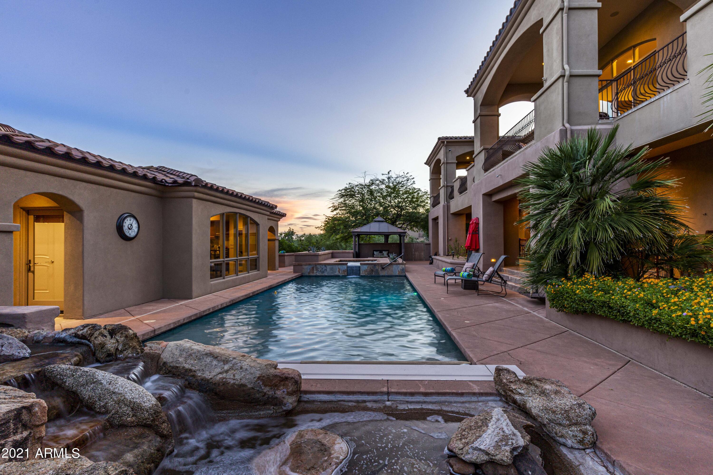 A magnificent estate built for comfortable living or lavish entertaining. Perched in the gated enclave of Eagle Mountain, this exceptional property boasts endless city light & mountain views.  For the car enthusiast this EIGHT car climate controlled garage is for you!  The home provides a total of 7523 square feet of which 575 square feet can be found in the private guest quarters complete with kitchenette and full bath.   In addition to the executive style office and powder room, the owner's suite stands alone. The breathtaking views will draw you to the private balcony which provides access to the backyard. The spa like bathroom will compel rejuvenation with the oversized steam shower, jetted tub, split dual vanities,  gorgeous stone throughout, and massive closet. Just off the formal dining and living rooms which have exceptional views, you will find the eat-in kitchen which is a culinary delight with an oversize wood paneled fridge, stainless steel double wall ovens, incredible woodwork, a Thermador gas cook-top with griddle and gorgeous granite.   A massive pantry is the icing on the cake as you will find plenty of room to store kitchen appliances as well as food!  You will also find a large laundry room with all the bells and whistles making doing laundry fun again.  Venture back to formal living and dining room, which are also surrounded by more views! These two formal spaces share a full size wet bar and a stand alone dual gas fireplace adding the ambiance you are looking for when entertaining or just sharing family time.  Take note of the Brazilian Tiger wood flooring as you take a stroll down one of the two staircases or the elevator and find yourself on the lower level complete with three en-suite bedrooms, a second quiet study area with built in cabinetry, and a media room that is better than being at the movies! There is even a small kitchenette and room for the popcorn machine.  The backyard is a true oasis with covered patios spanning both levels, a lap pool with motorized cover, spillover spa, a serene rock waterfall, a Pergola for additional outdoor dining, and the perfect amount of grass.  From the lower outdoor patio, you will also find direct access to the fitness room that rivals any gym!   Wind up to the expansive upper balcony and take in those views! You will have plenty of room for outdoor dining or chaise lounges to enjoy a good book and soak in those mountain views. It is on this level you will find an outdoor BBQ, and built in fireplace perfect for roasting marshmallows on those cool winter nights.  Access to the garage can also be found here.    This mammoth 8 car garage is perfect for all the toys and holds a second laundry facility.   HVAC units, pool pumps, water heater, and water filtration system have all been replaced in the last 3 years!  This is truly a one of a kind Fountain Hills Estates that will be well received by all.  Come see for yourself.